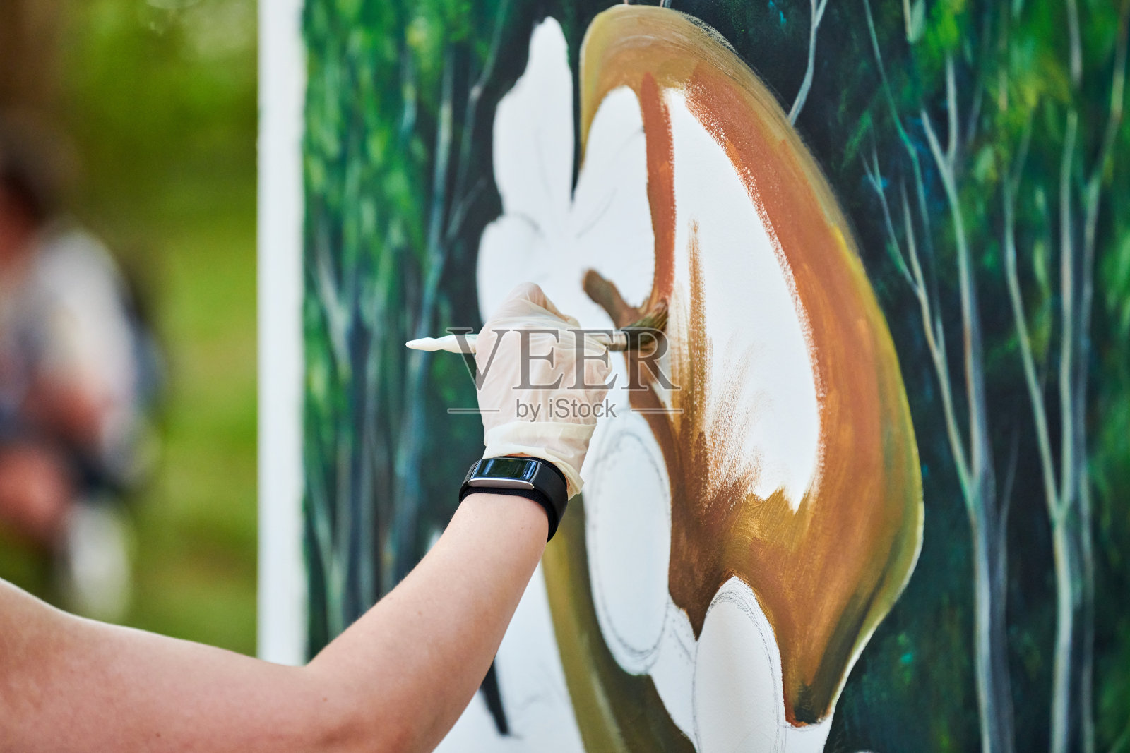 女孩艺术家手握画笔,在画布上绘制绿色自然景观照片摄影图片