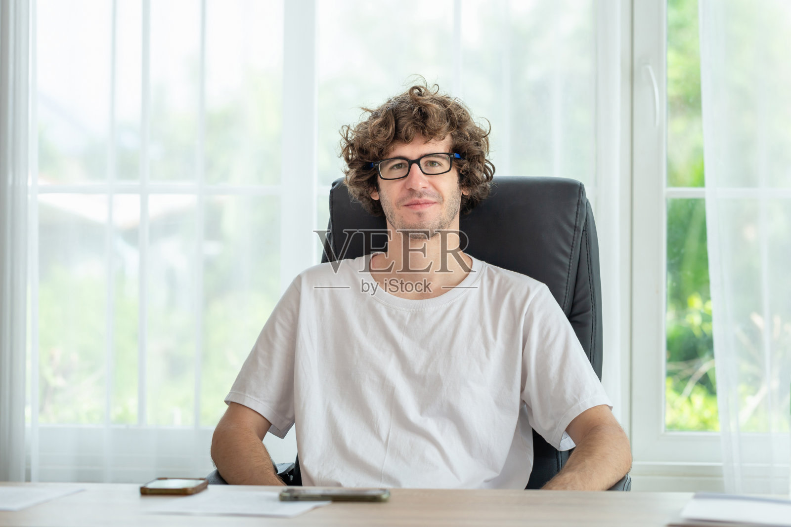 随意的男人放松地坐在房间里,微笑的男人看着镜头照片摄影图片