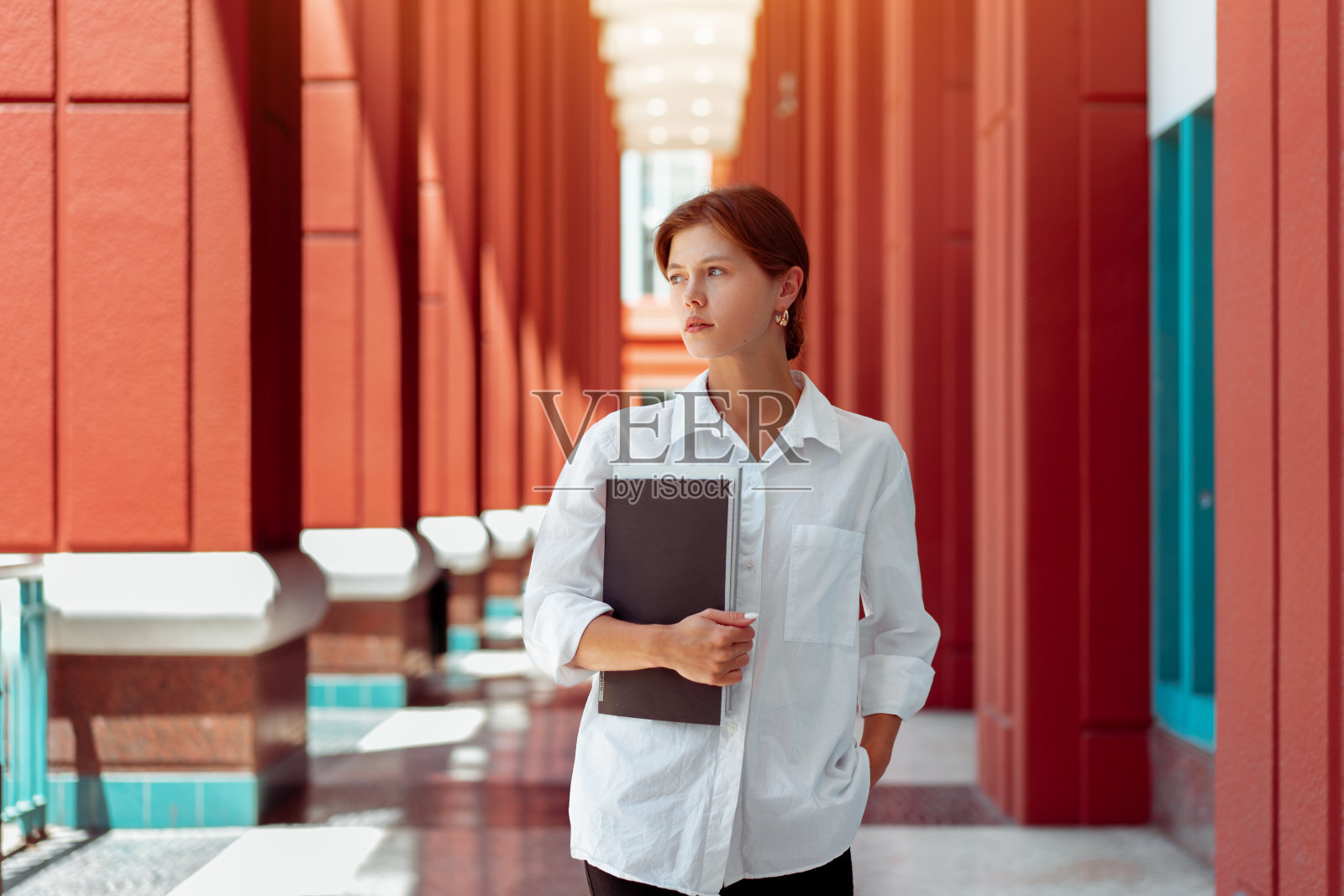 商人肖像。白人女性商务人士站在户外,拿着商务单据夹。照片摄影图片