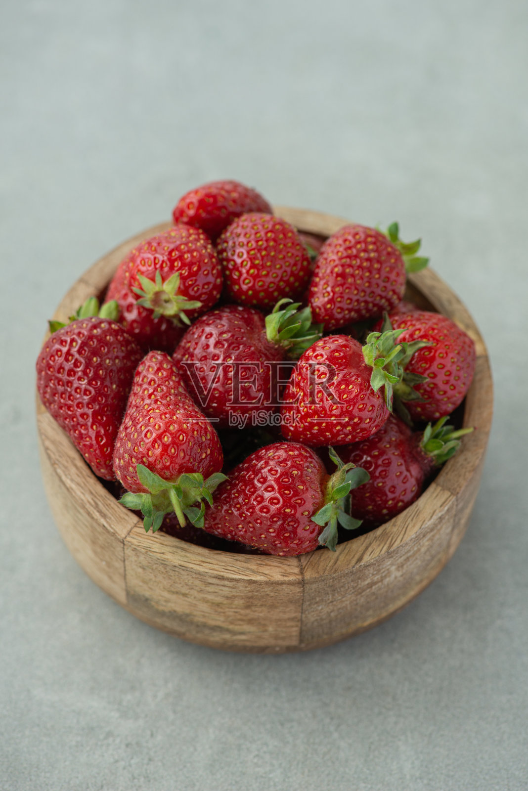 木制盘子里的草莓被隔离在灰色的背景上照片摄影图片