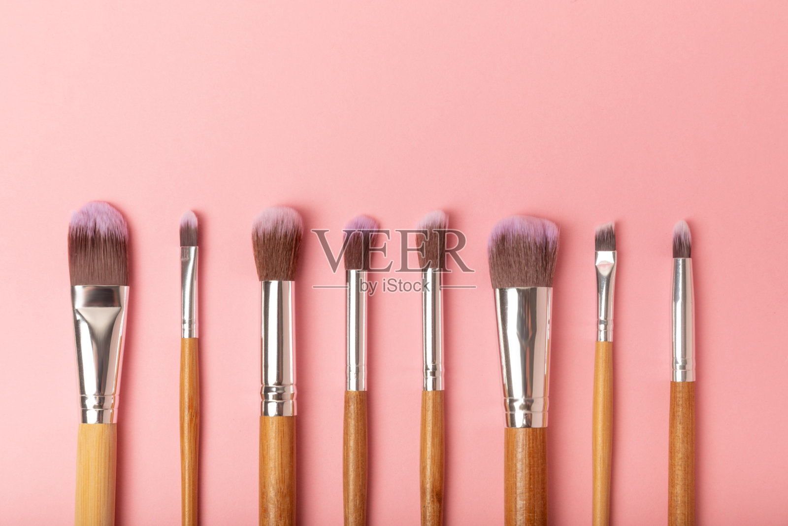 化妆用的化妆品。化妆刷在粉红色的背景上。创意时尚理念。化妆刷的集合,俯视图,横幅。平的。照片摄影图片