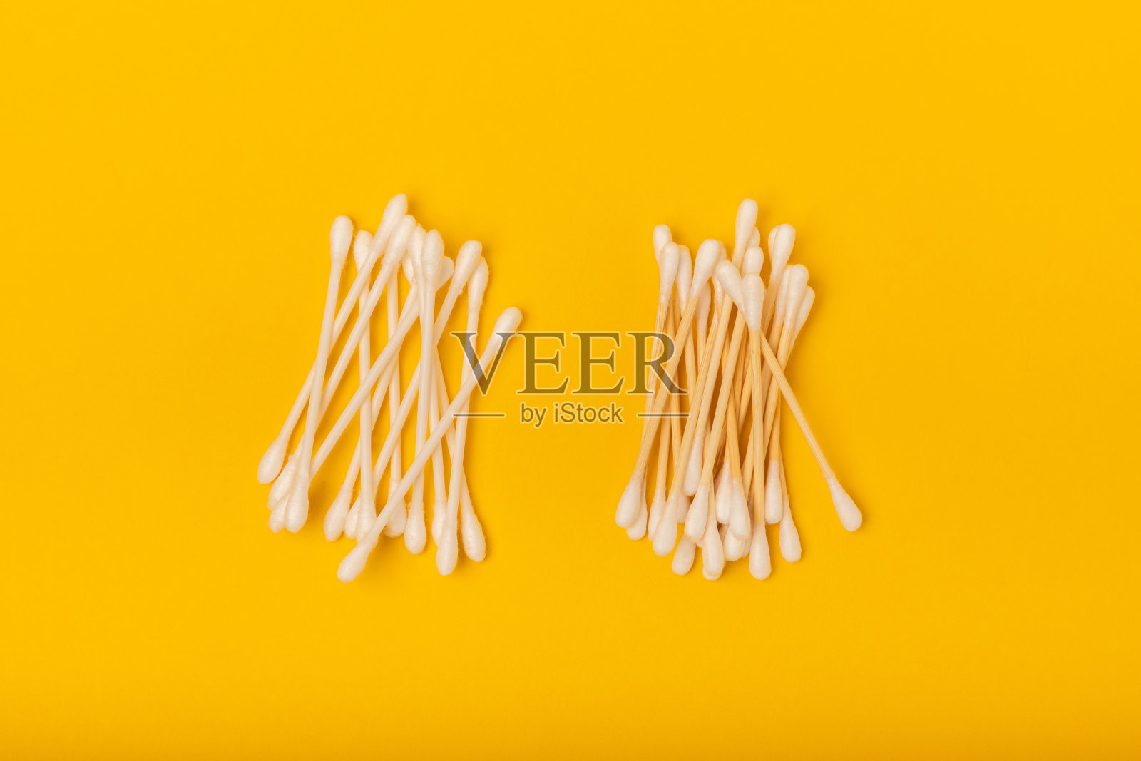 亮黄色背景上的棉花芽。环保材料。白色背景上的木制棉签。竹签和棉花。零废弃物,无塑料的生活理念。放文字的地方。照片摄影图片
