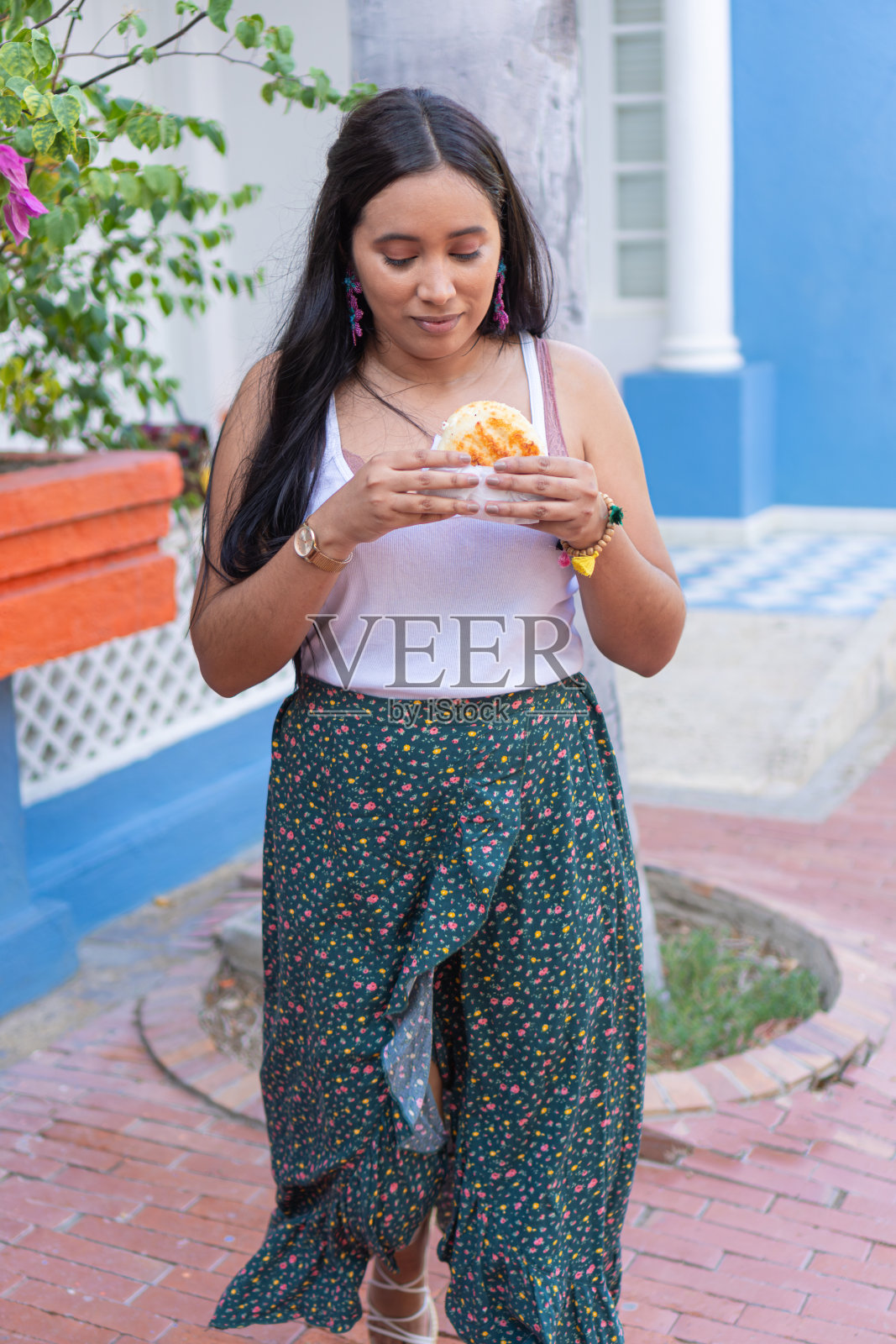 女人在街上吃玉米饼照片摄影图片