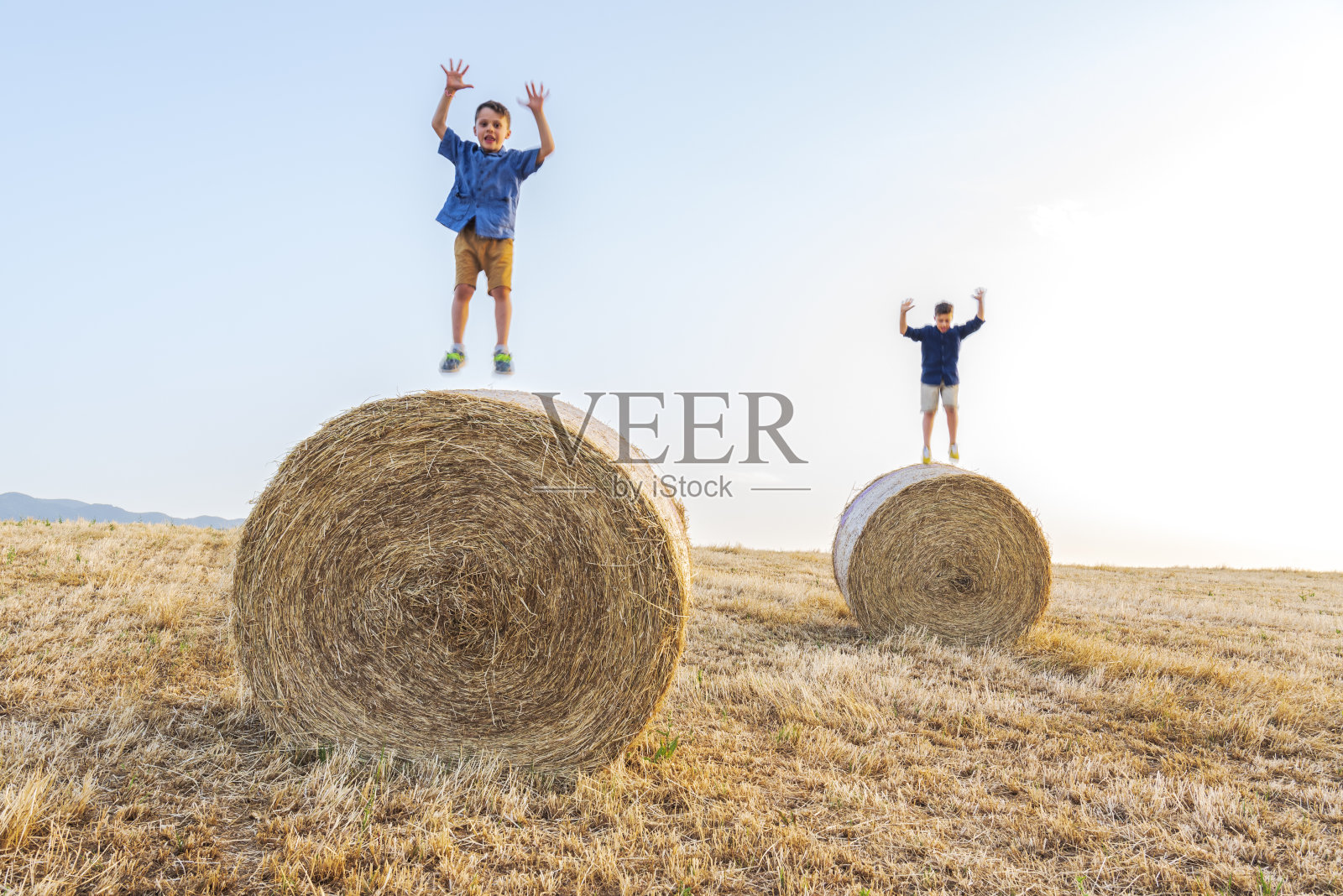 小男孩在干草捆上跳跃照片摄影图片