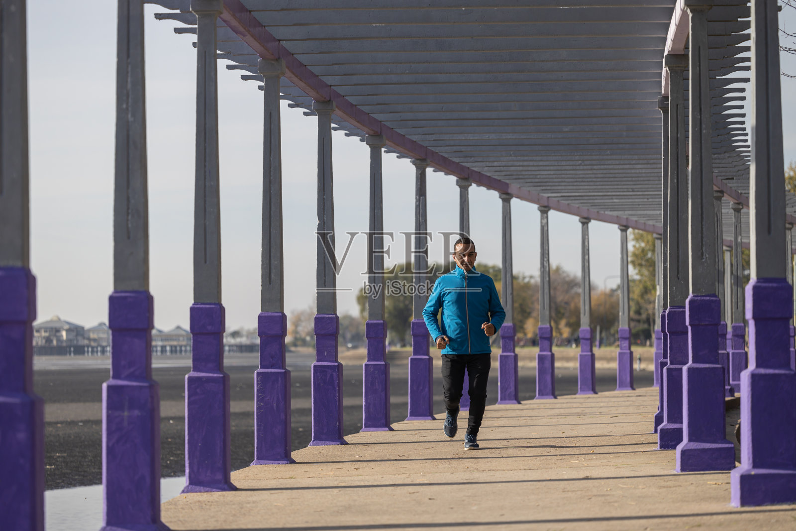 年轻的拉丁裔男子跑过公园的凉棚。照片摄影图片