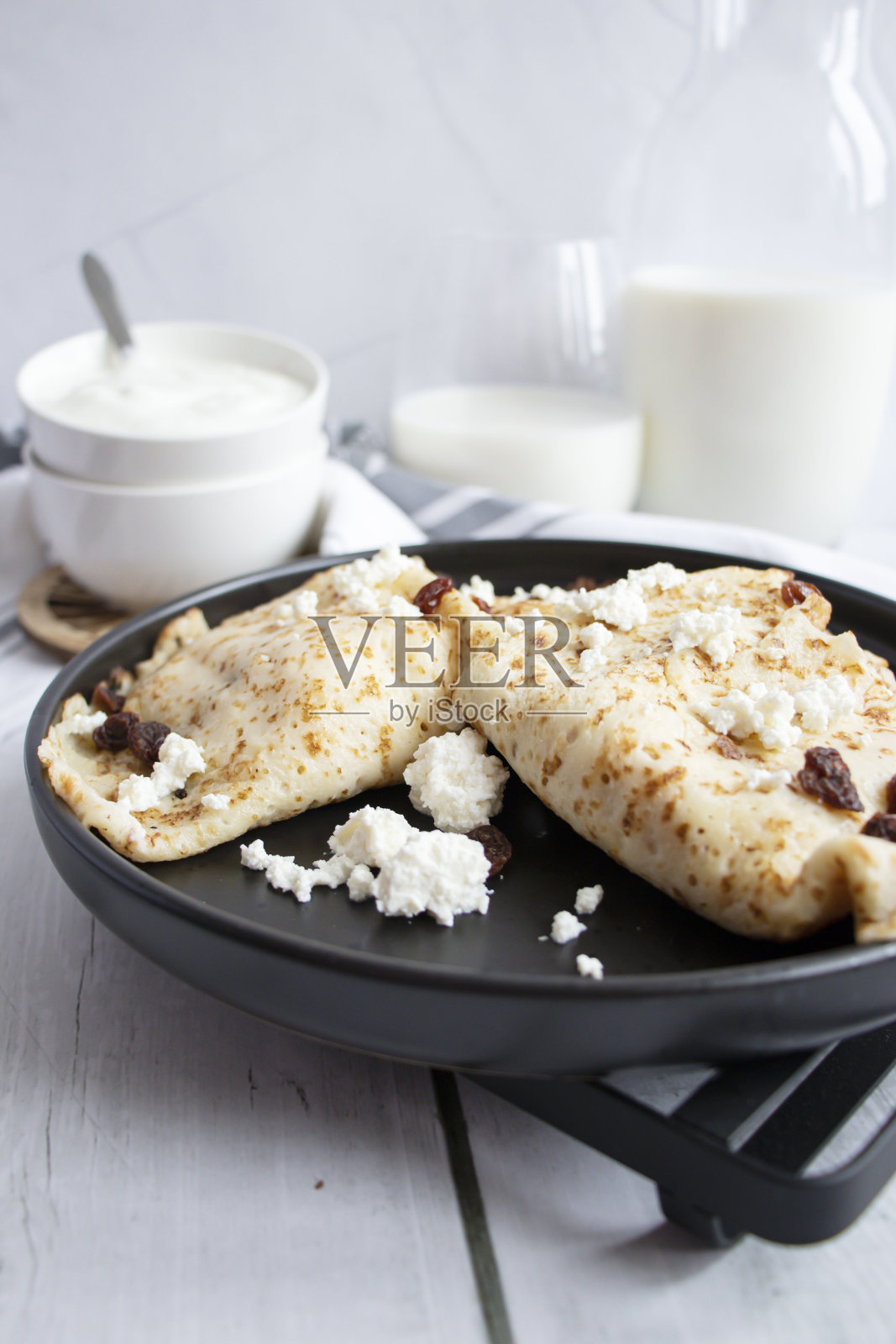 盘子里放着奶酪和葡萄干的煎饼。木制背景照片摄影图片