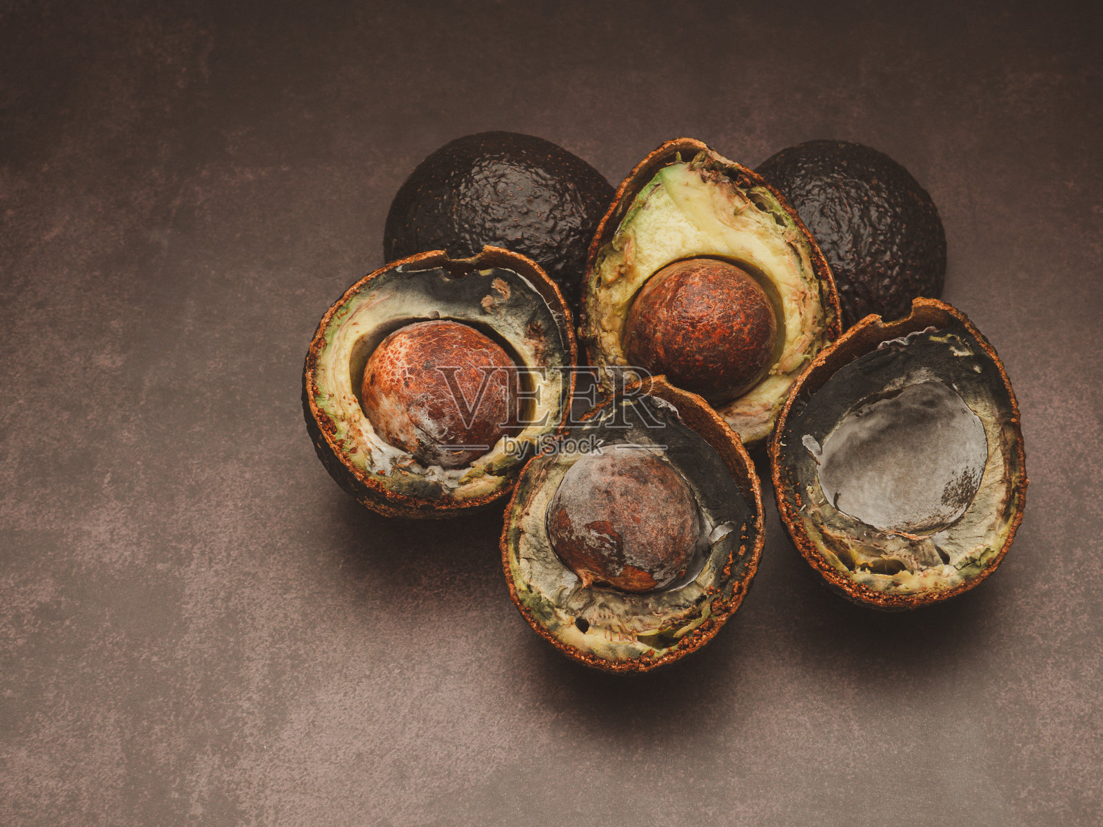 在灰色的背景上,腐烂的牛油果切成两半。照片摄影图片