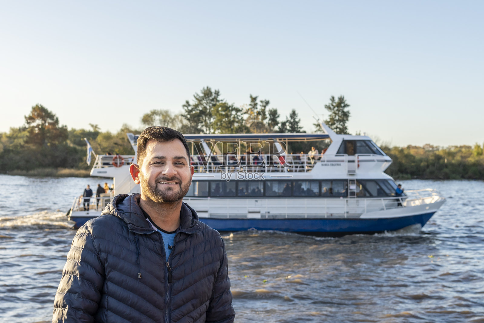 一个拉丁男子在河上的一艘船前摆姿势照片摄影图片