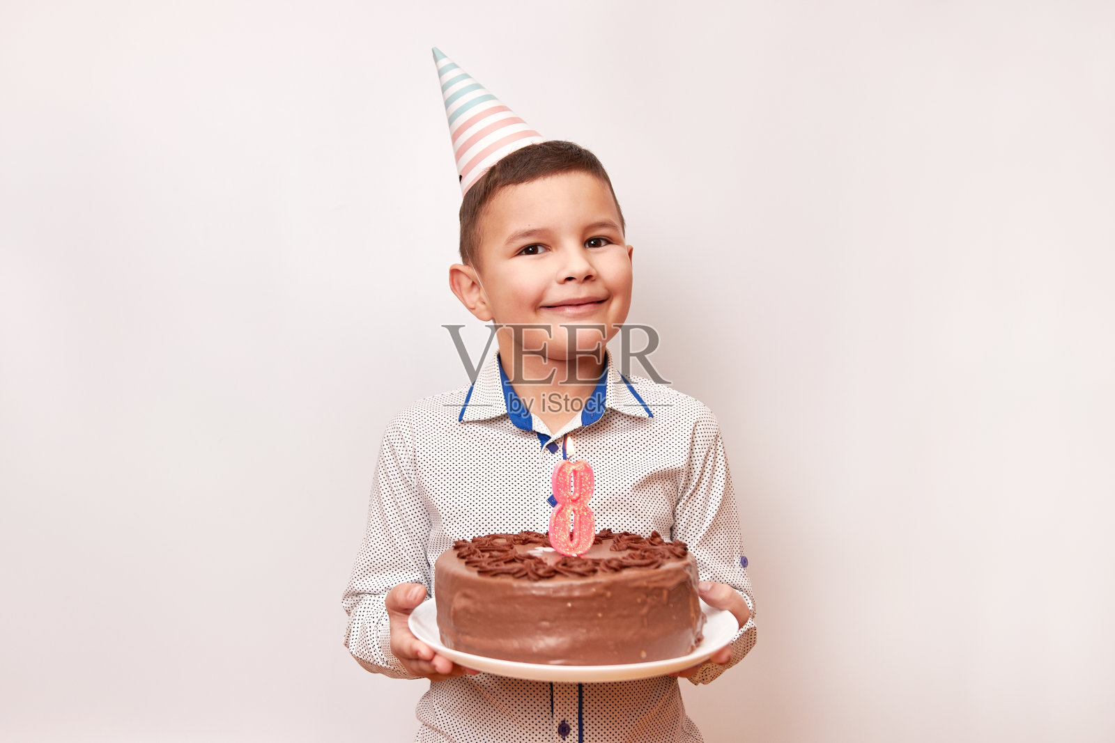 欢快的男孩拿着一个节日蛋糕,上面插着数字8形状的蜡烛。生日庆祝概念。照片摄影图片