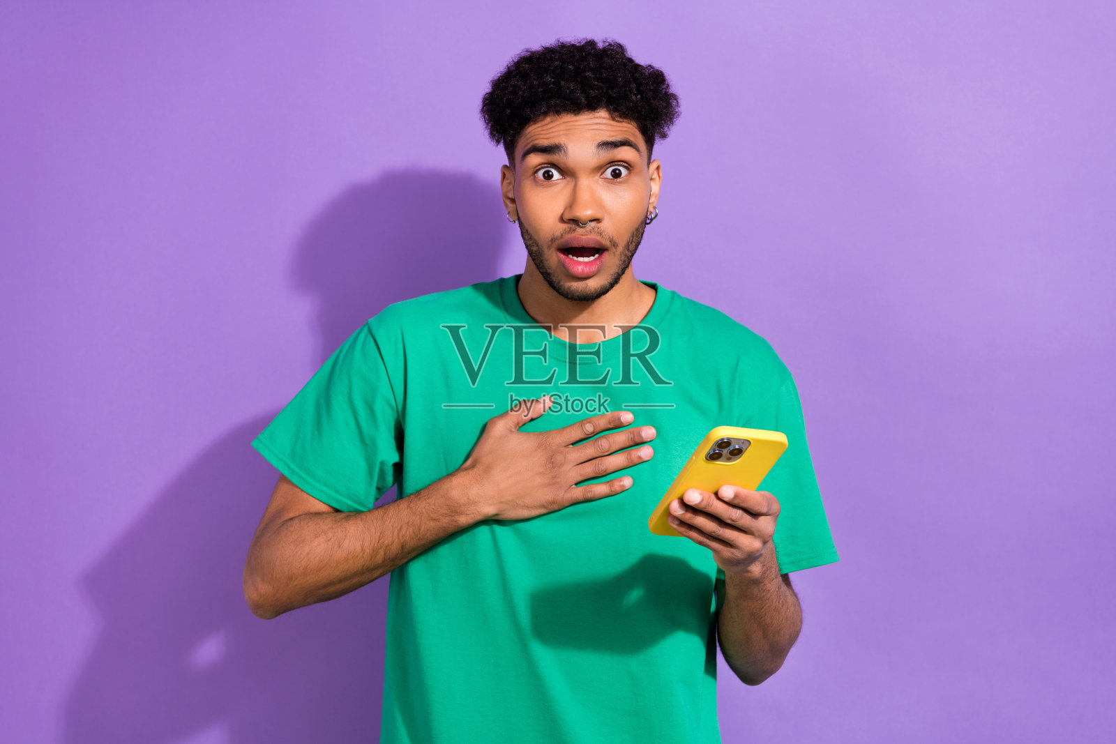 印象深刻的时髦的家伙穿着绿色t恤阅读新闻现代设备孤立的紫色背景的照片照片摄影图片