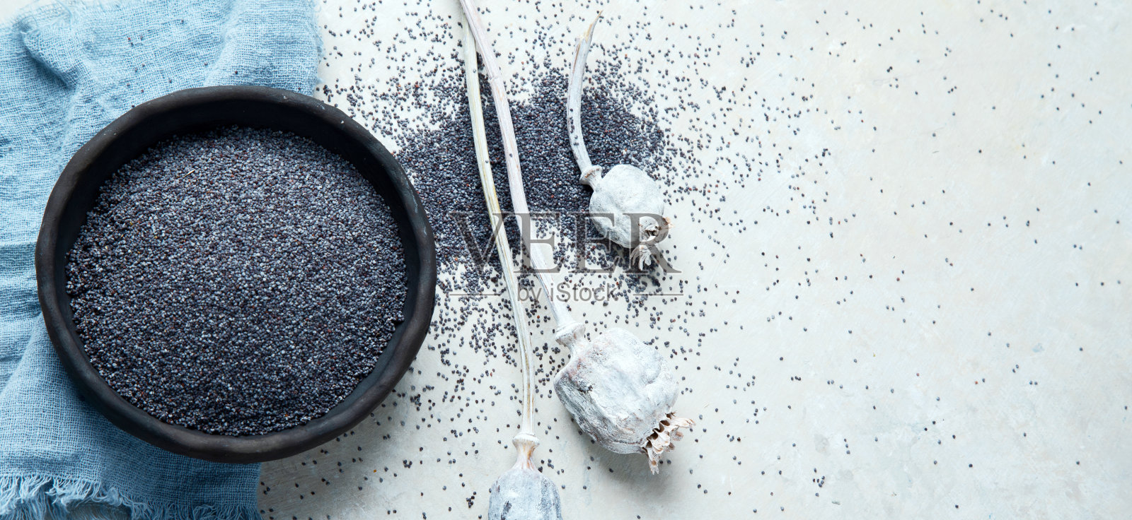 在灰色背景上与罂粟种子组合。照片摄影图片