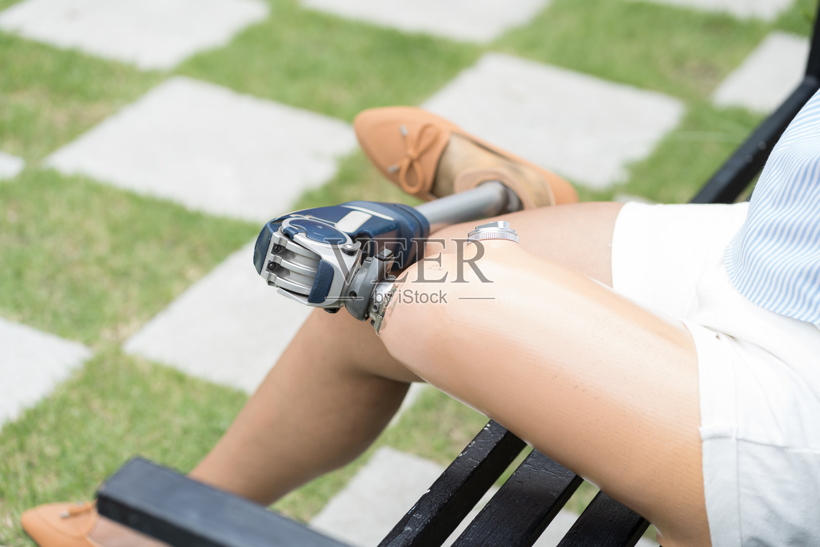 截肢的女人。戴着假腿的女性坐在户外的花园里。戴着义肢的女助残。带着假肢的亚洲女人在户外照片摄影图片