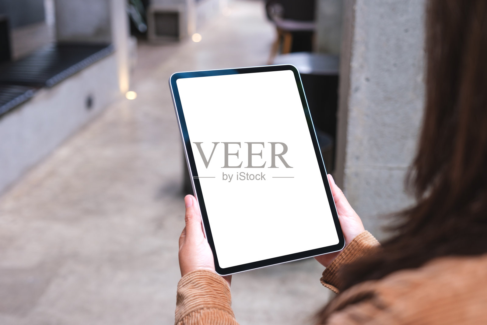 咖啡厅里,一个女人拿着数字平板电脑,屏幕是空白的照片摄影图片