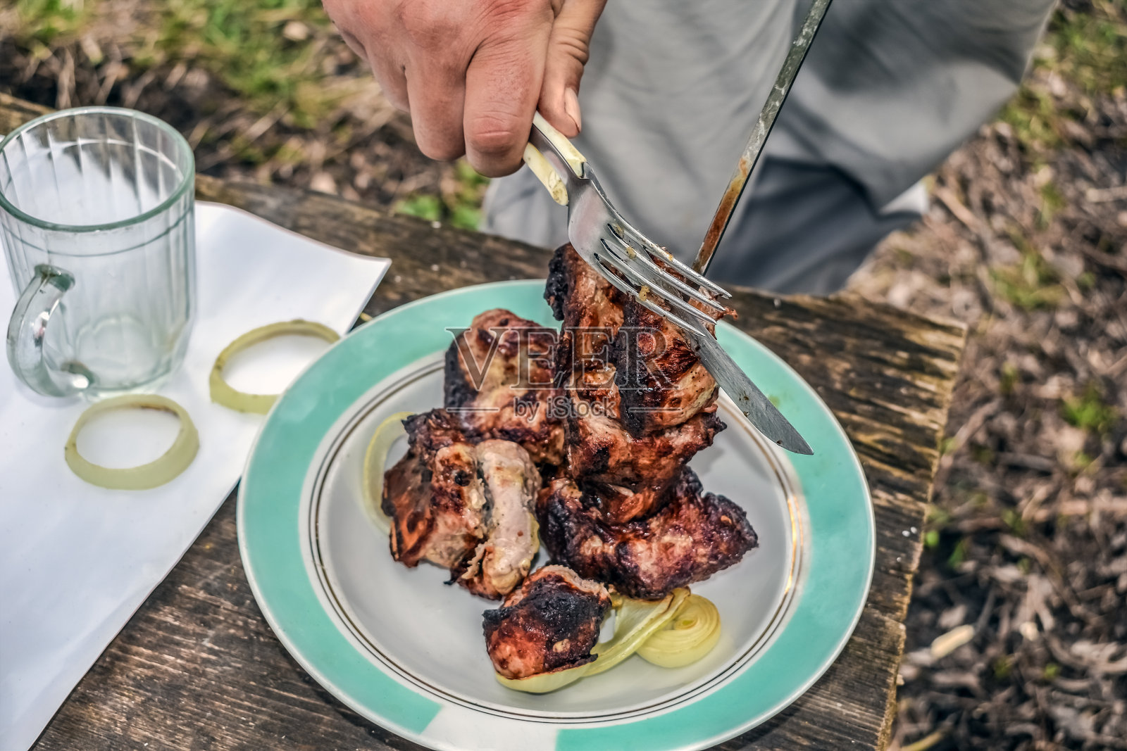 男人的手从烤肉串上拿下来,在露天的火上烤着照片摄影图片