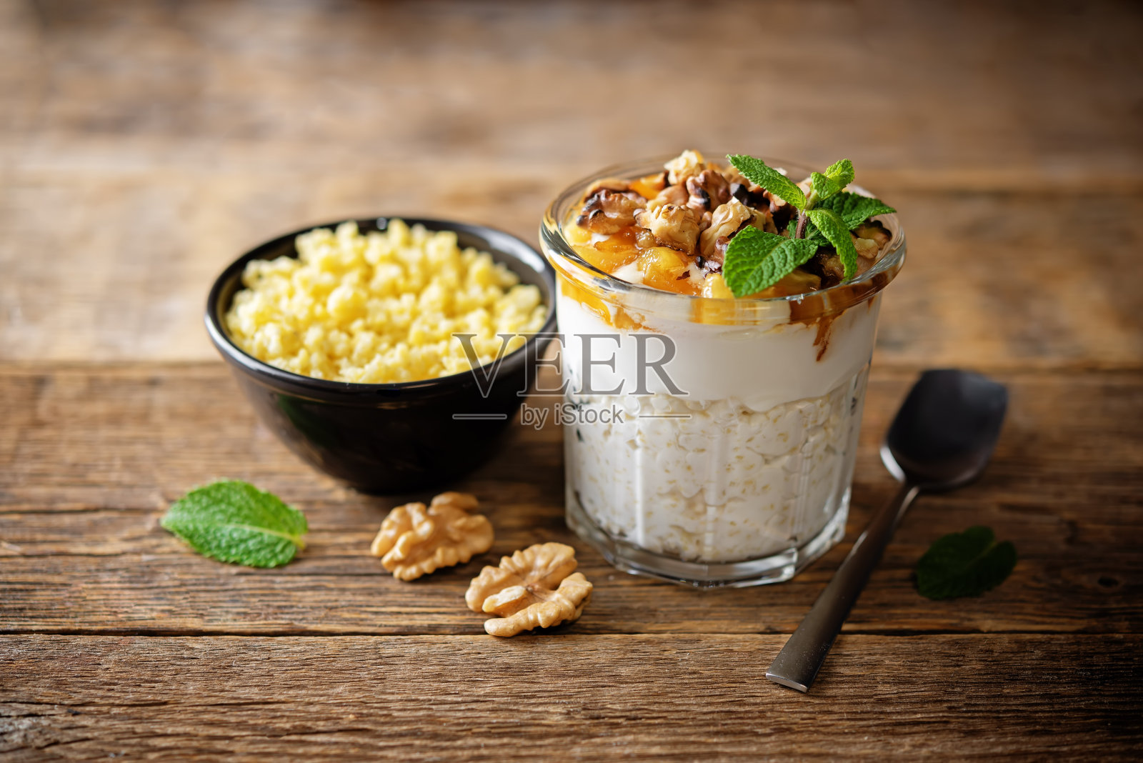 希腊酸奶,小米,焦糖苹果,核桃,在玻璃杯里照片摄影图片