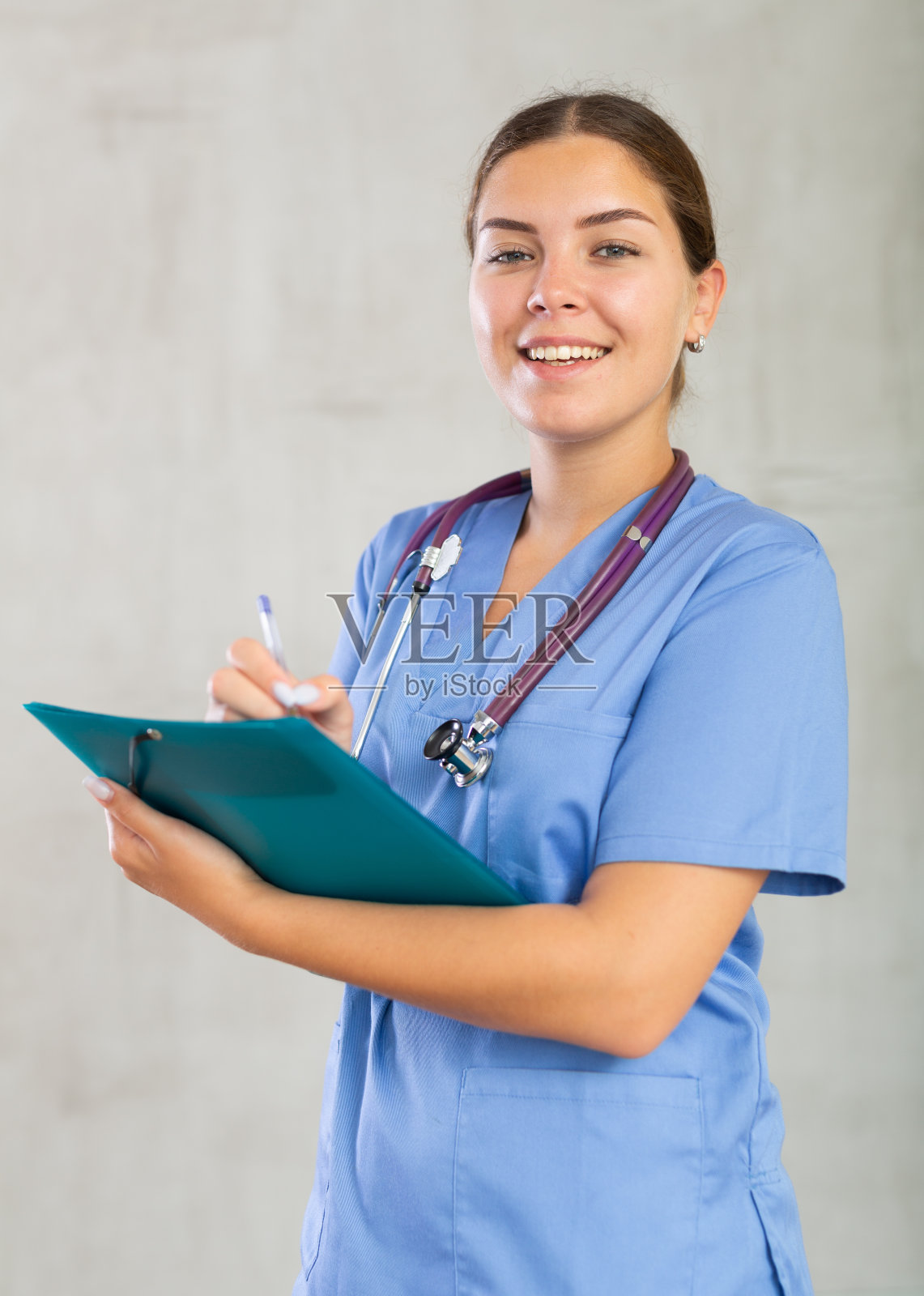 穿着医疗服的年轻女子在做笔记照片摄影图片