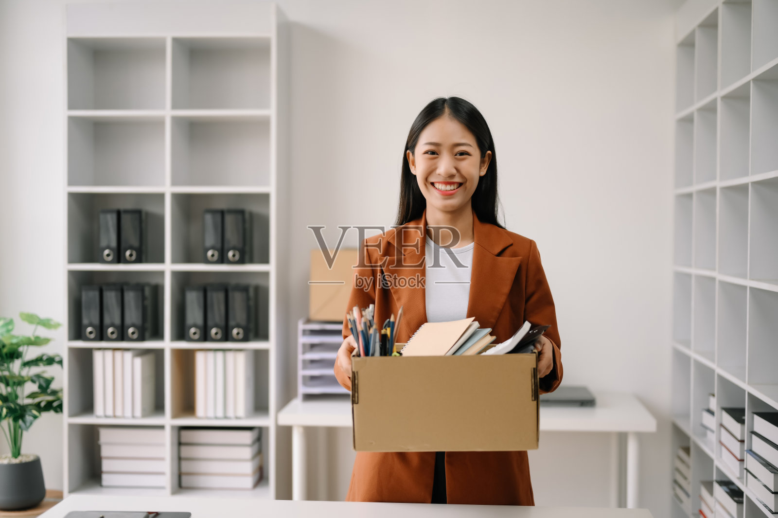 快乐和兴奋的年轻漂亮的亚洲女性办公室职员庆祝她的辞职,带着她的私人物品。离职,换公司。在办公室照片摄影图片