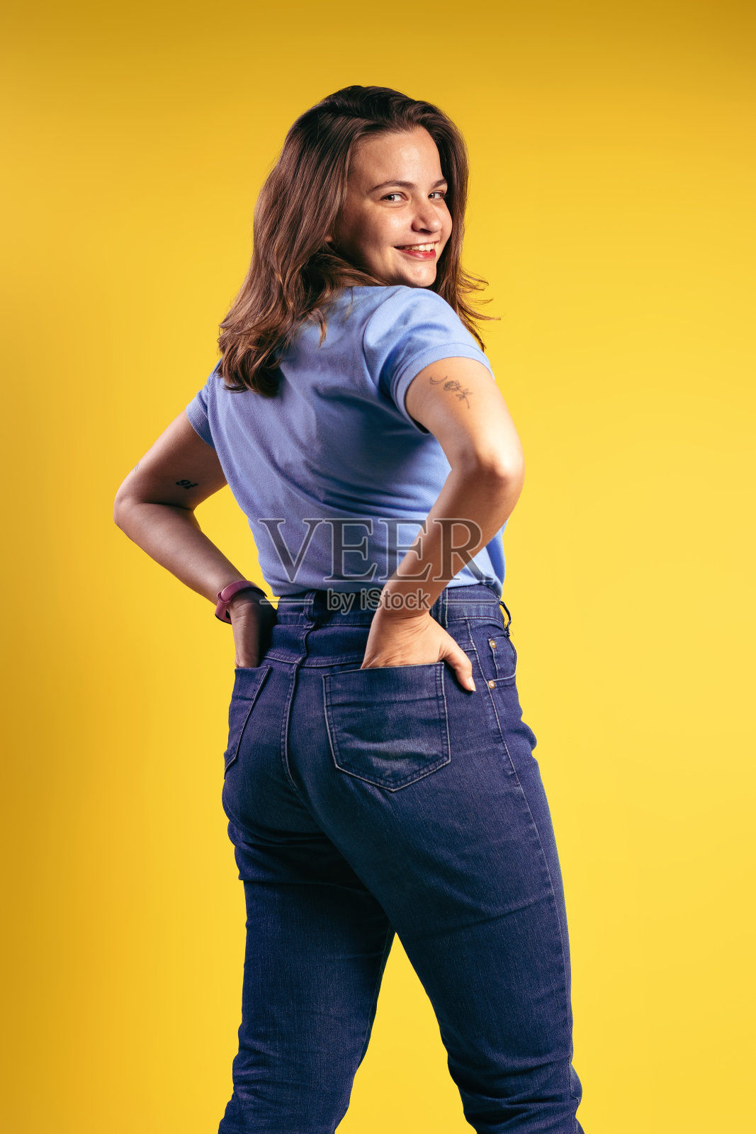 一个巴西女人的肖像,穿着polo衫和牛仔裤,部分背对着相机,双手放在后口袋里,微笑着- bel<s:1> - par<e:1> -巴西照片摄影图片