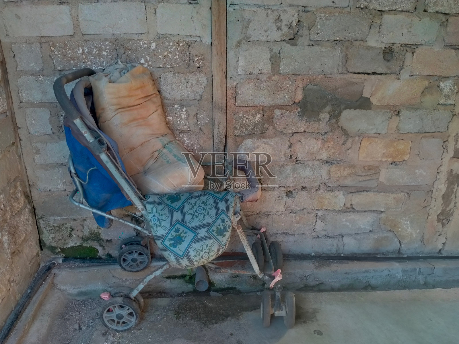 废弃在房子后面的破旧婴儿车和旧枕头照片摄影图片
