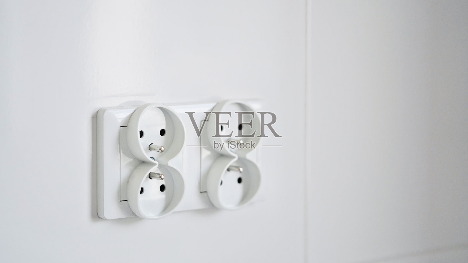 白色墙壁上隔离的双欧式电源插座的特写镜头。装修新公寓的厨房。副本的空间。照片摄影图片