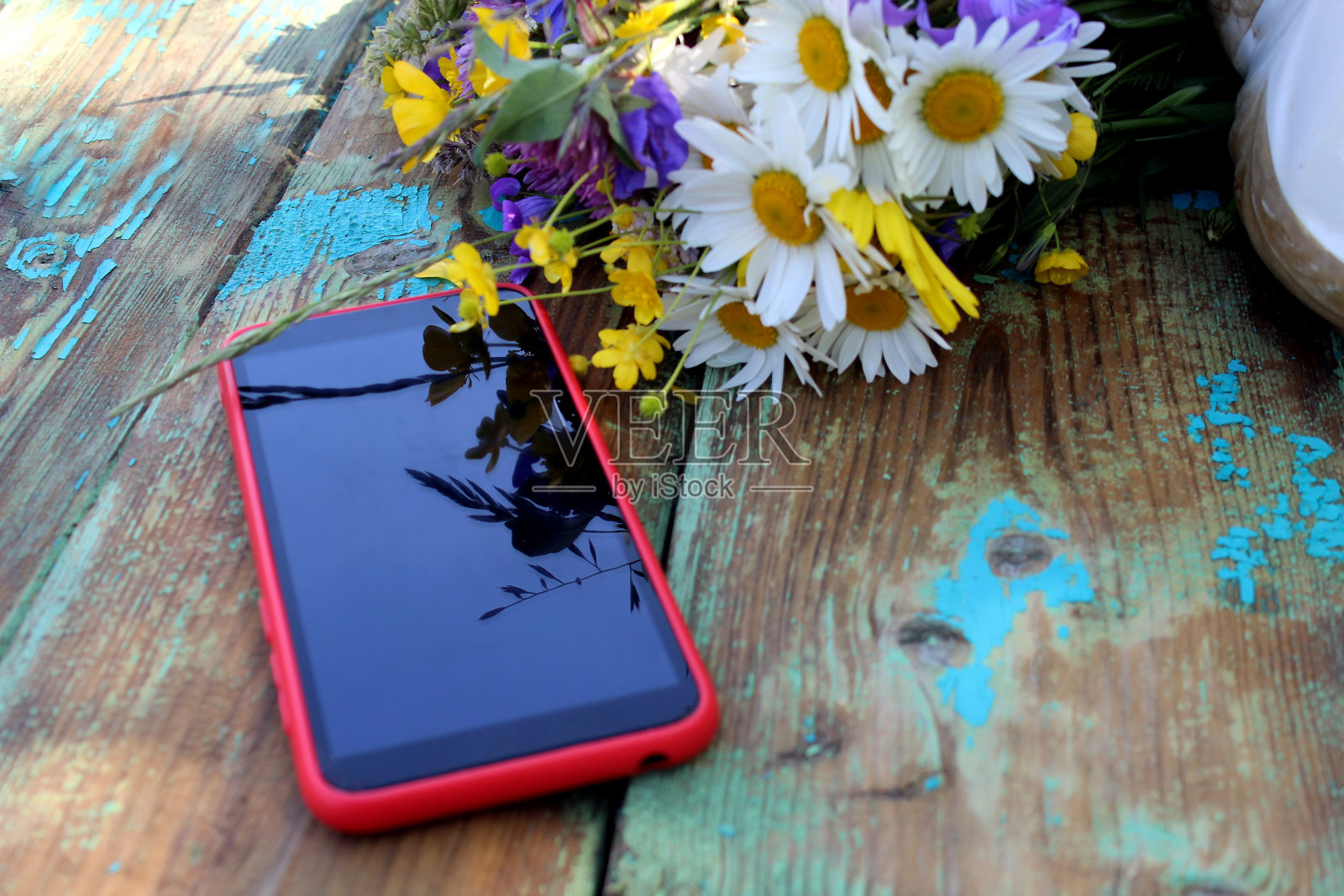 桌上放着一部电话和一束野花。照片摄影图片