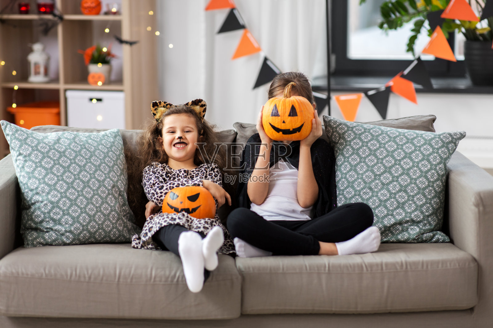 女孩们穿着万圣节服装,家里有南瓜照片摄影图片