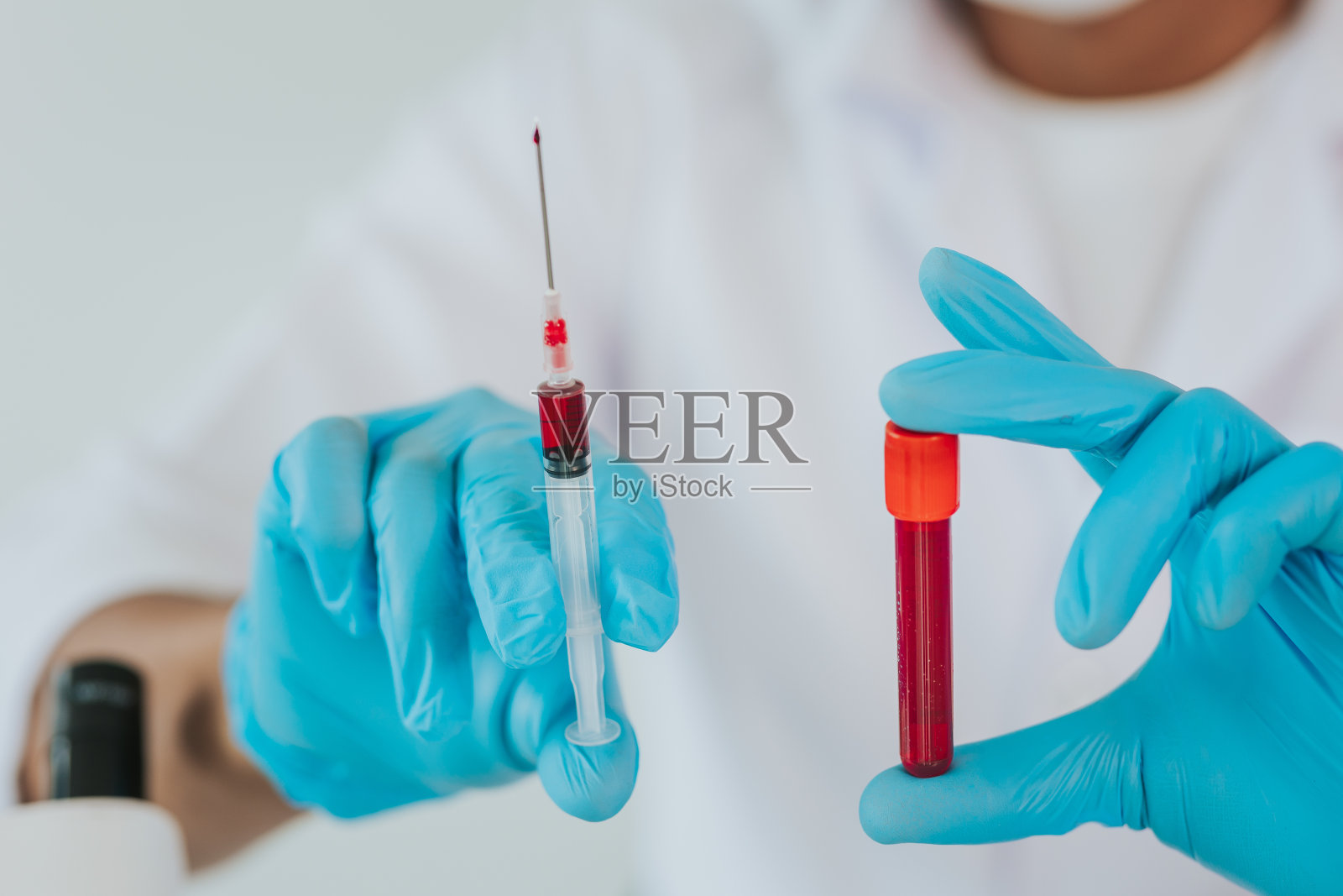 在实验室里,医生从架子上拿起一根血样管,上面有一台分析仪。实验室里拿着试管的技术人员照片摄影图片