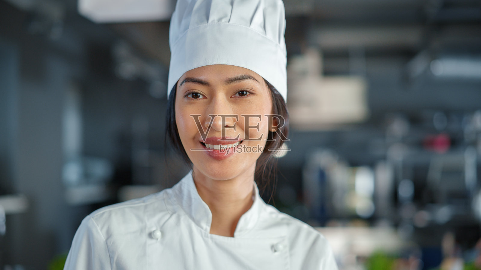 世界名店:亚洲女厨师在现代专业厨房里摆造型,转身看镜头,微笑。烹饪美味,健康,正宗的菜肴。照片摄影图片