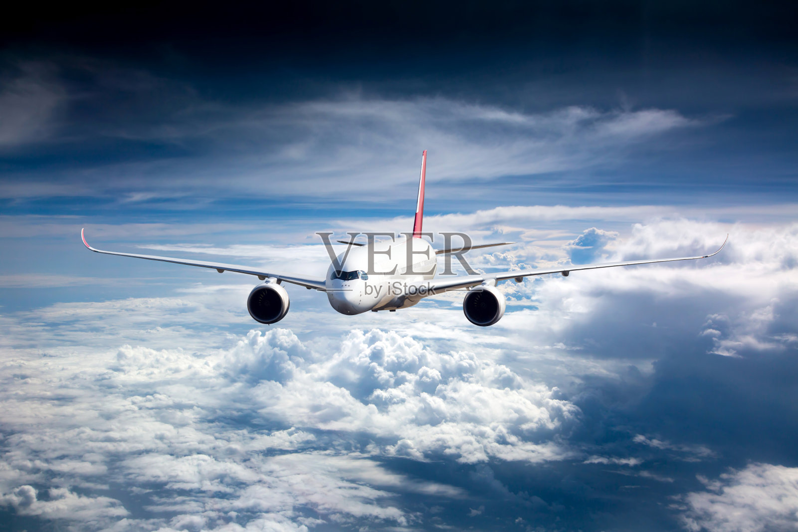 客机在云层上方高高飞行。前视图。照片摄影图片