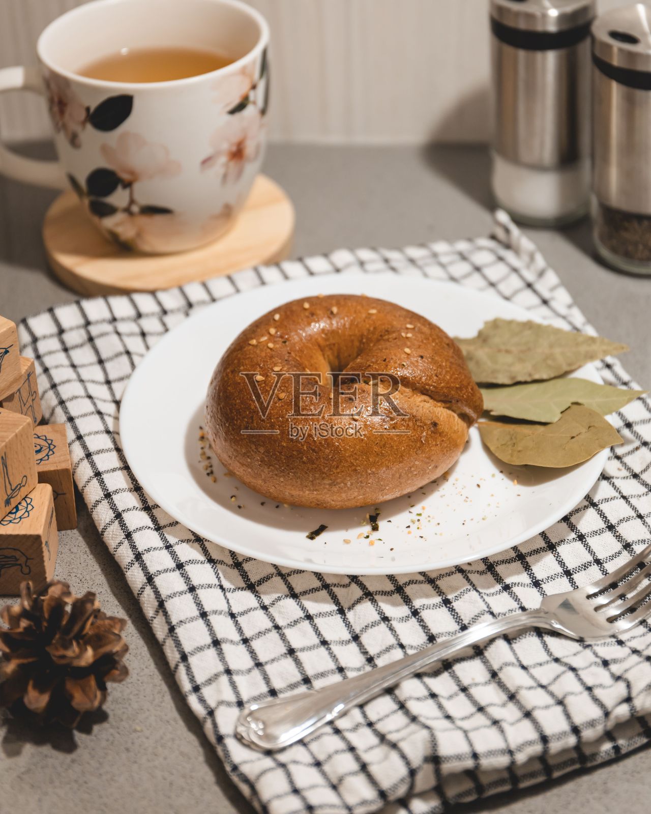 刚烤好的百吉饼放在一个白色的盘子上,它脆脆的金棕色表面在阳光下闪闪发光照片摄影图片