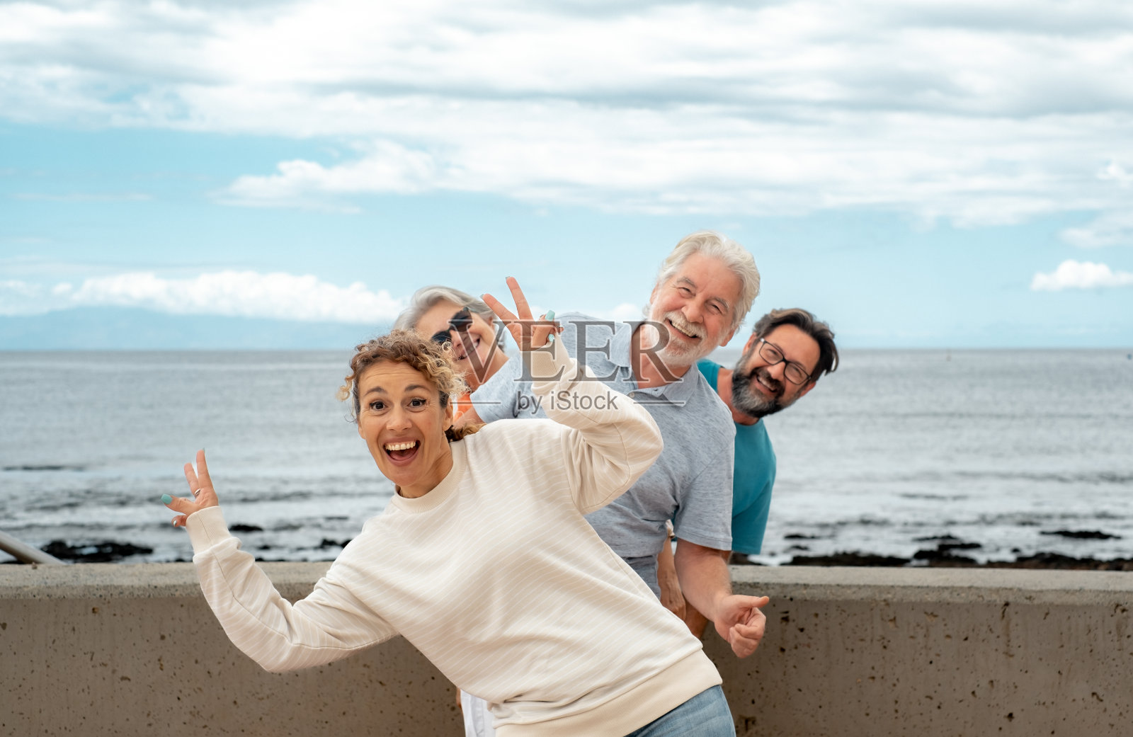 快乐的多代家庭在海上度假,在户外一起玩乐,微笑无忧无虑。年迈的父母,成熟的儿子和媳妇照片摄影图片