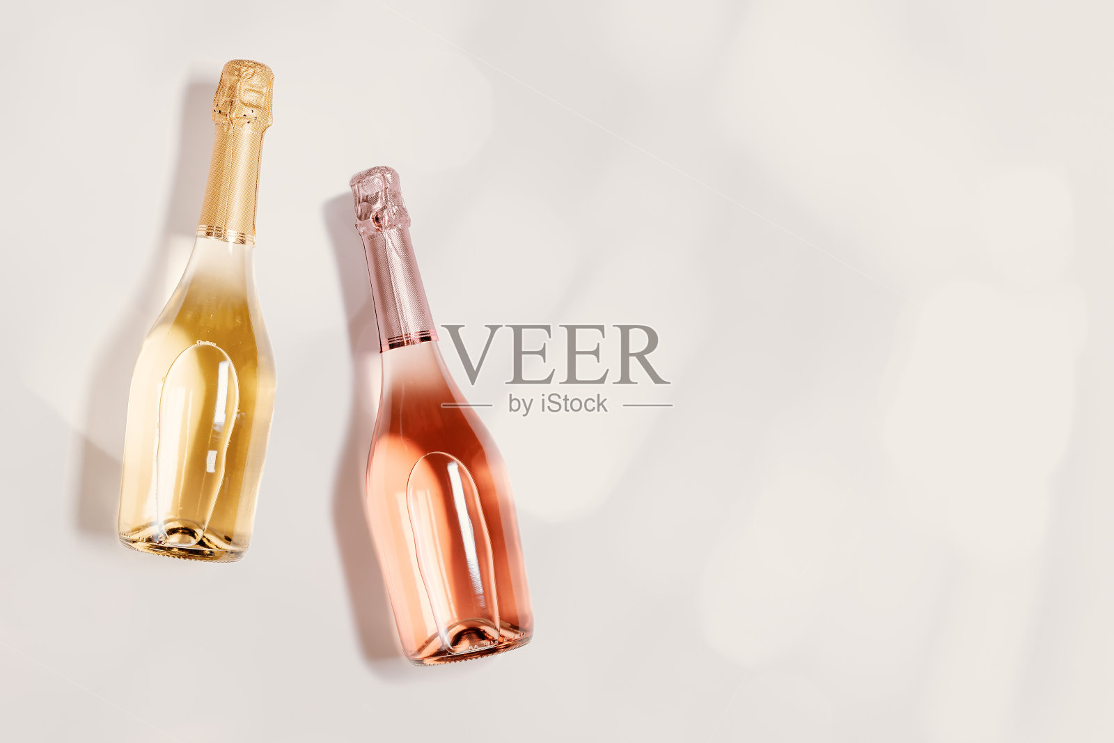 俯视图起泡酒,瓶玫瑰和白色香槟与散景米色,复制空间。喜庆酒饮,婚宴酒饮概念,米色粉彩背景,简约风格照片摄影图片