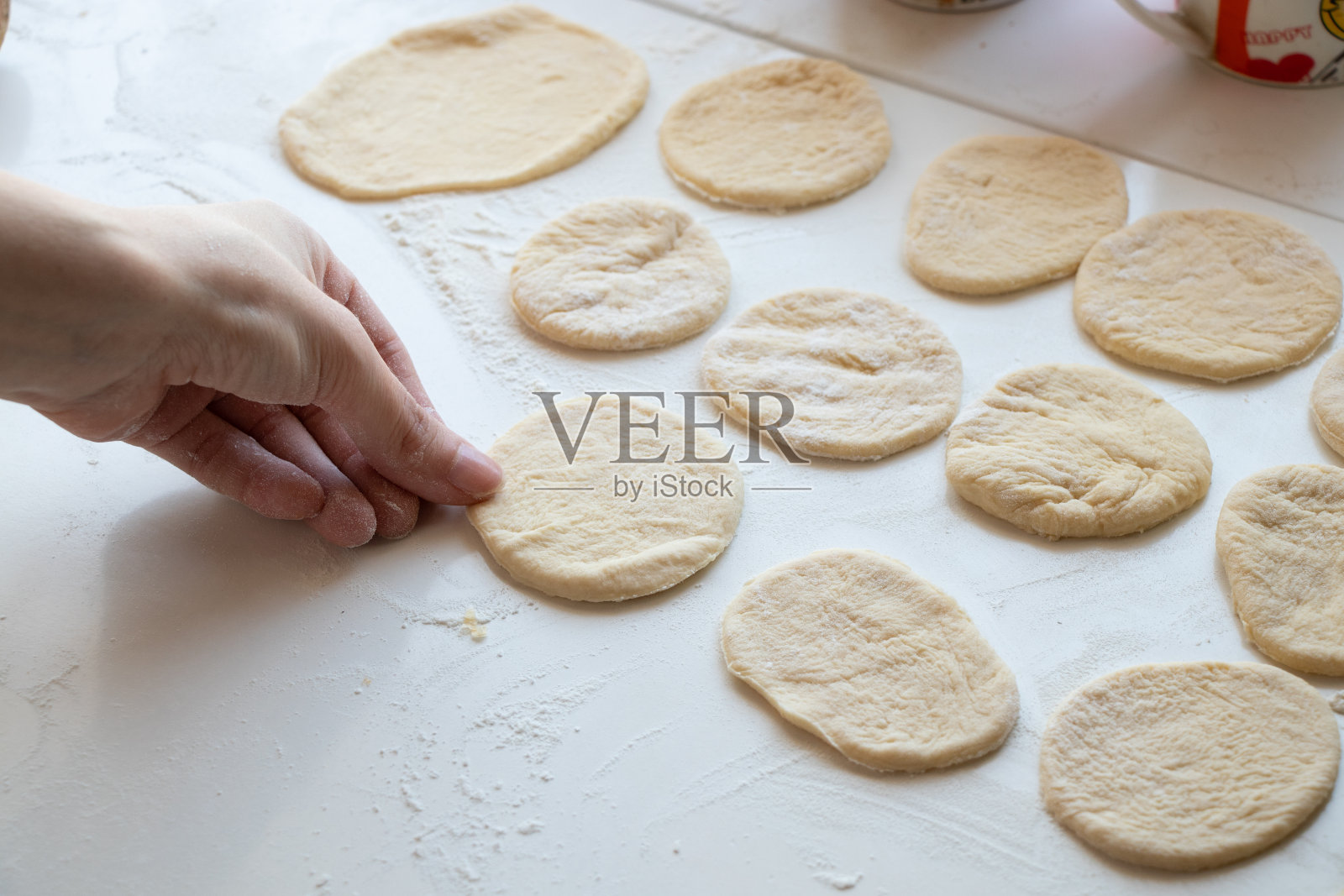 厨房里一张白色的桌子上,女性的手在揉生面团照片摄影图片