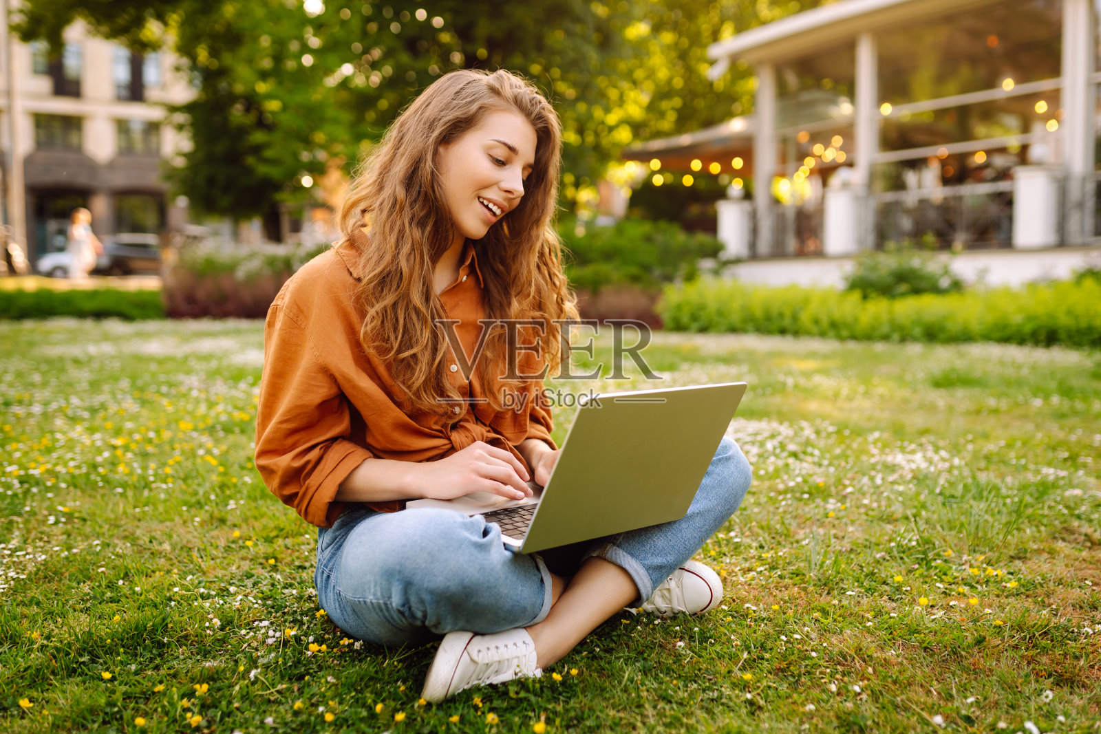 微笑着的年轻女子拿着一台笔记本电脑在户外工作或在线学习。照片摄影图片