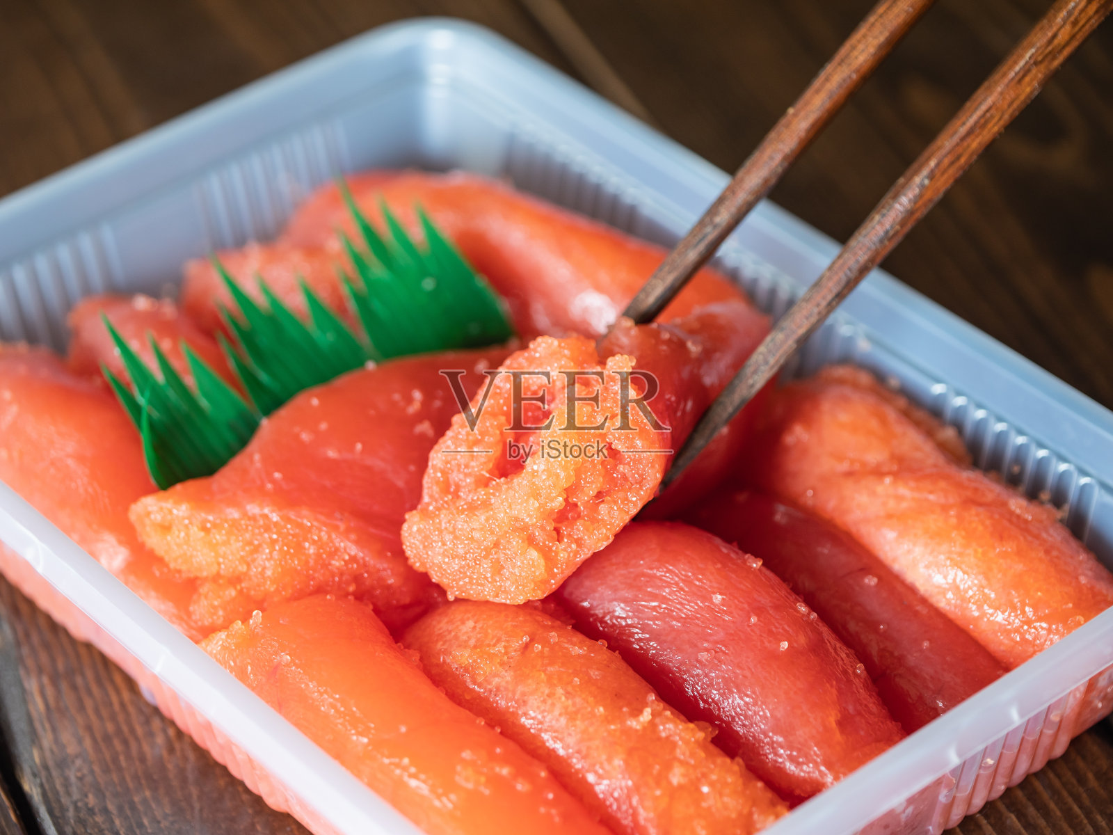 日本明太子装在塑料容器里。用辣椒腌制的鳕鱼籽。照片摄影图片