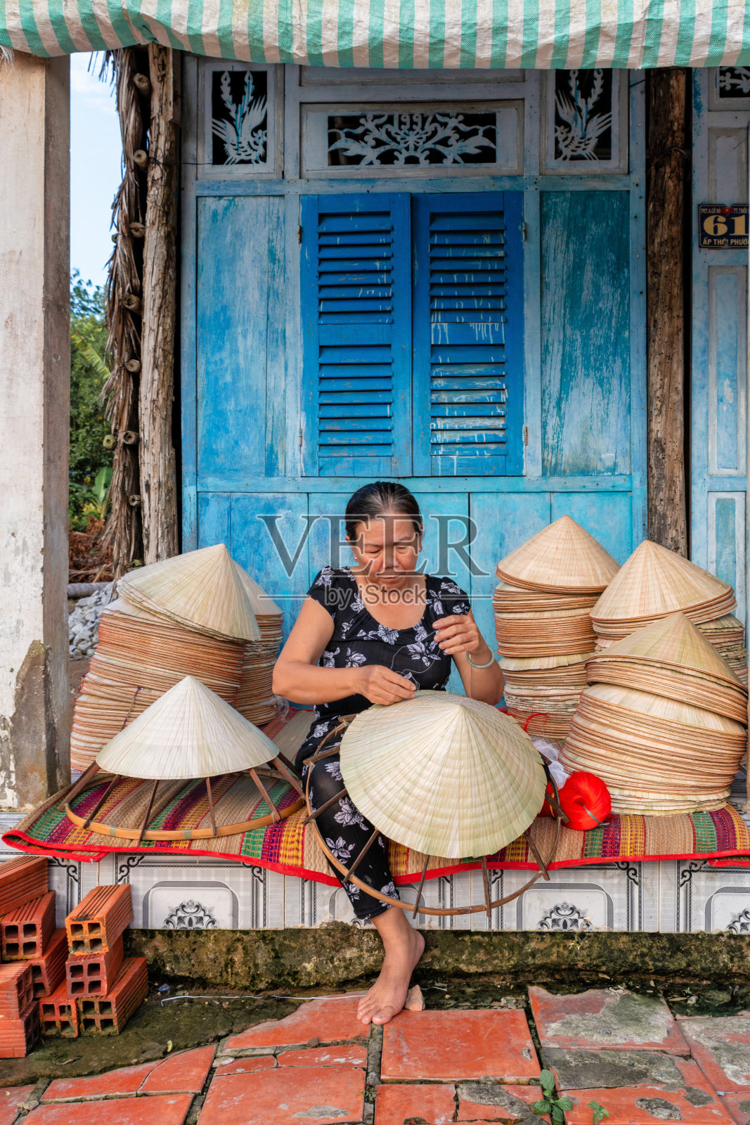 越南老妇人正在家中制作一顶传统的圆锥形帽子照片摄影图片