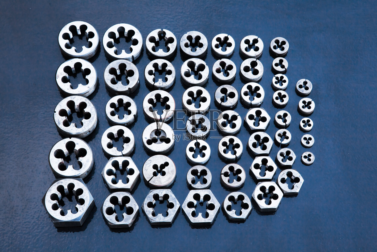 螺栓螺纹模。许多不同尺寸的模具,俯视图。在螺栓上制作螺纹的手工工具。照片摄影图片