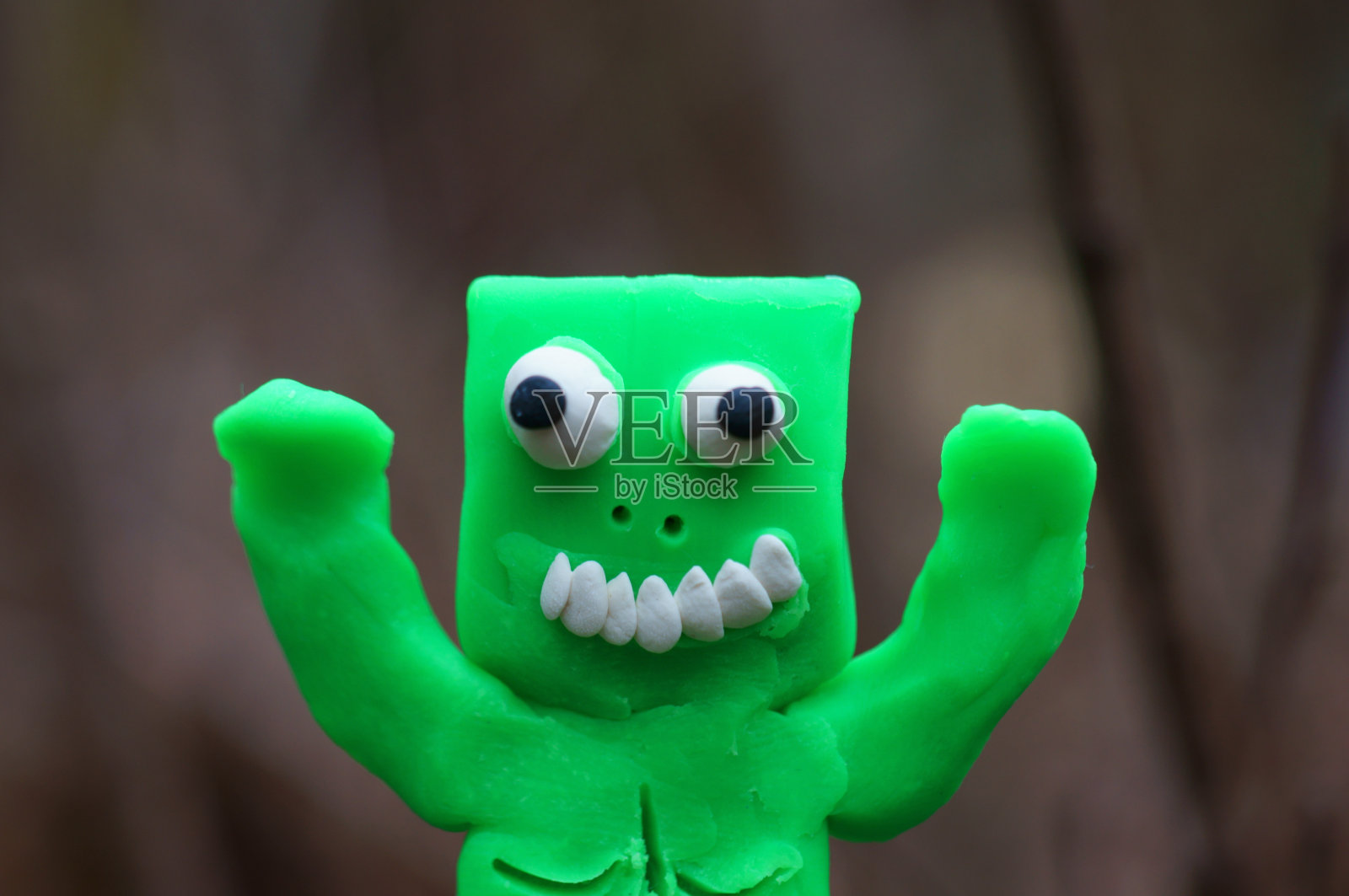 绿色橡皮泥做的有趣的怪物。照片摄影图片