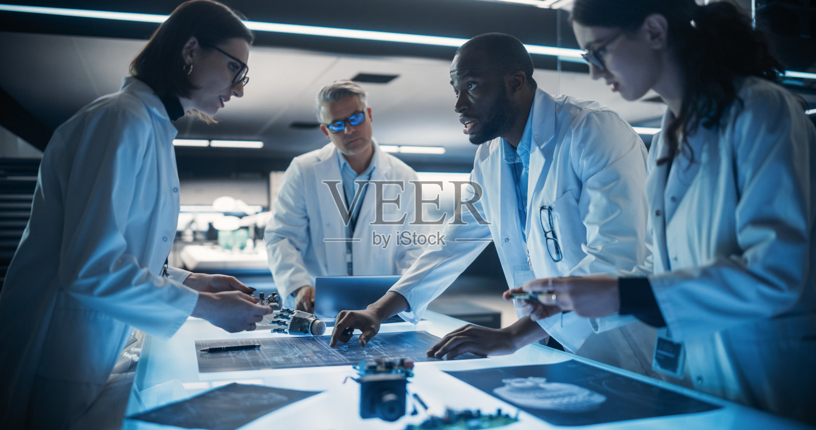 多元化的工业机器人专家团队在先进的研究设施中研究创新的假手。年轻工程师讨论原型,测试电子细节。照片摄影图片