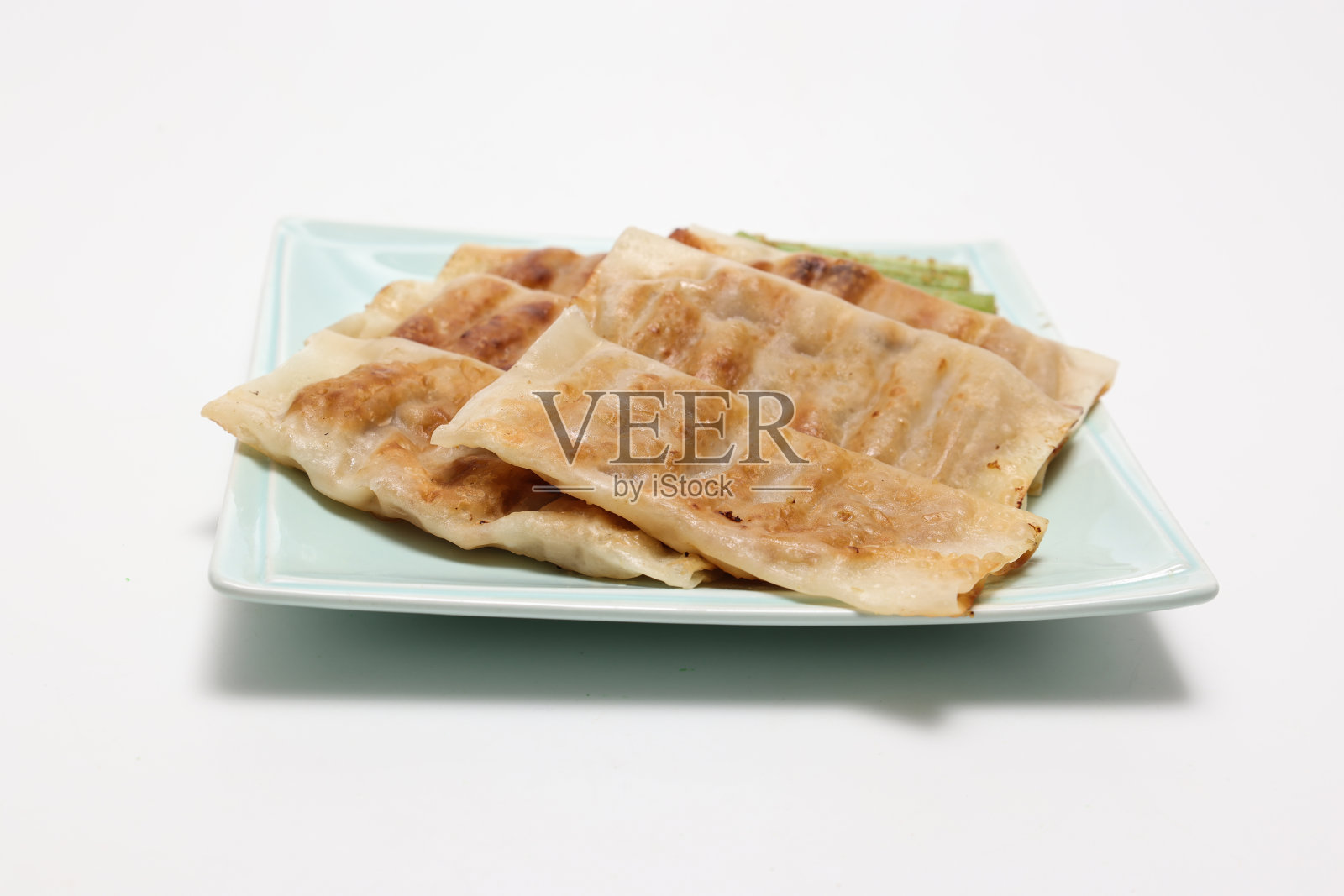 在白色的背景上孤立的蓝色盘子上的棍状饺子。照片摄影图片