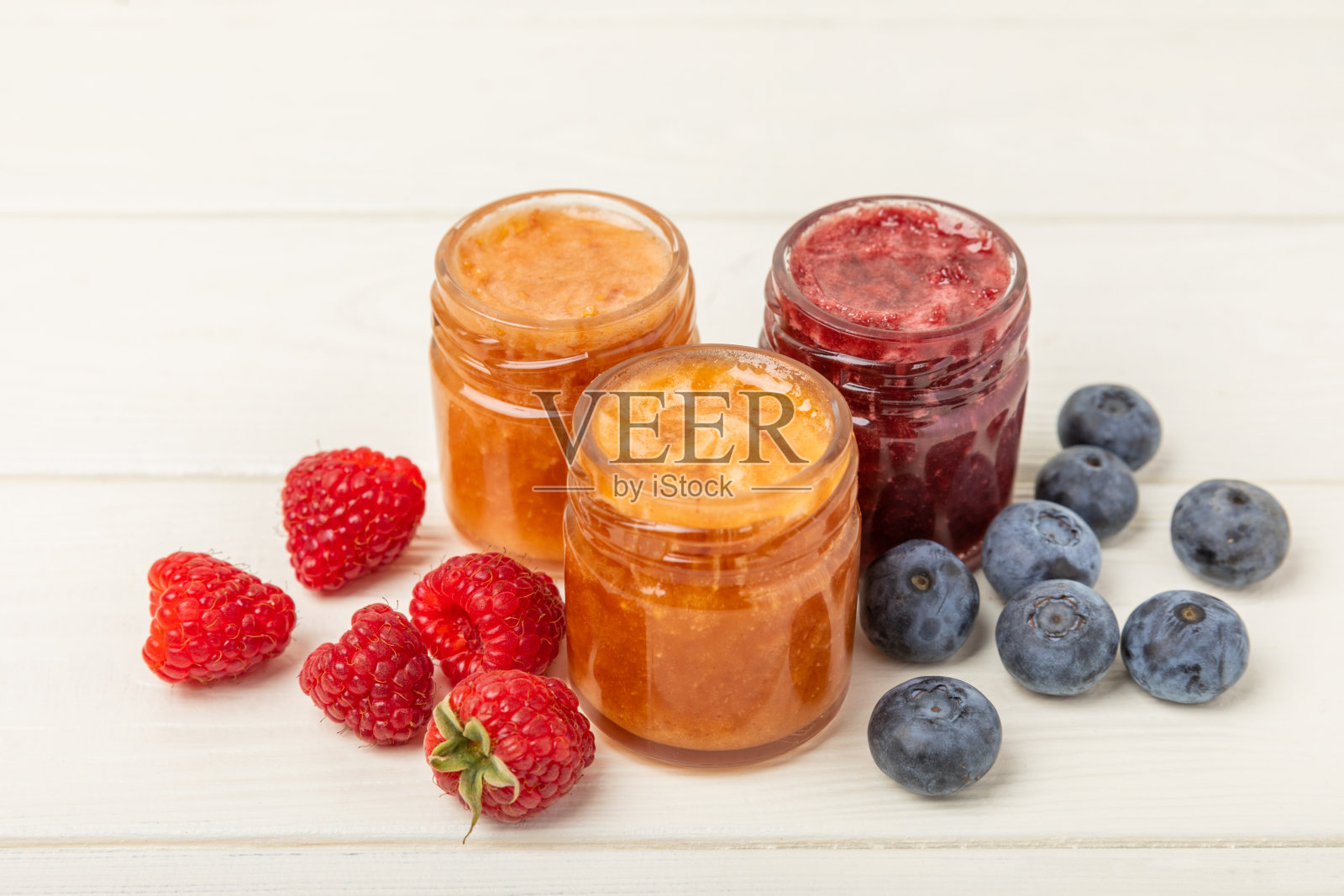 一罐蜂蜜。水果蜂蜜配覆盆子、蓝莓、杏仁和开心果。健康和美丽的果酱。蜂蜜膏。素食的有机产品。副本的空间。副本的空间。照片摄影图片