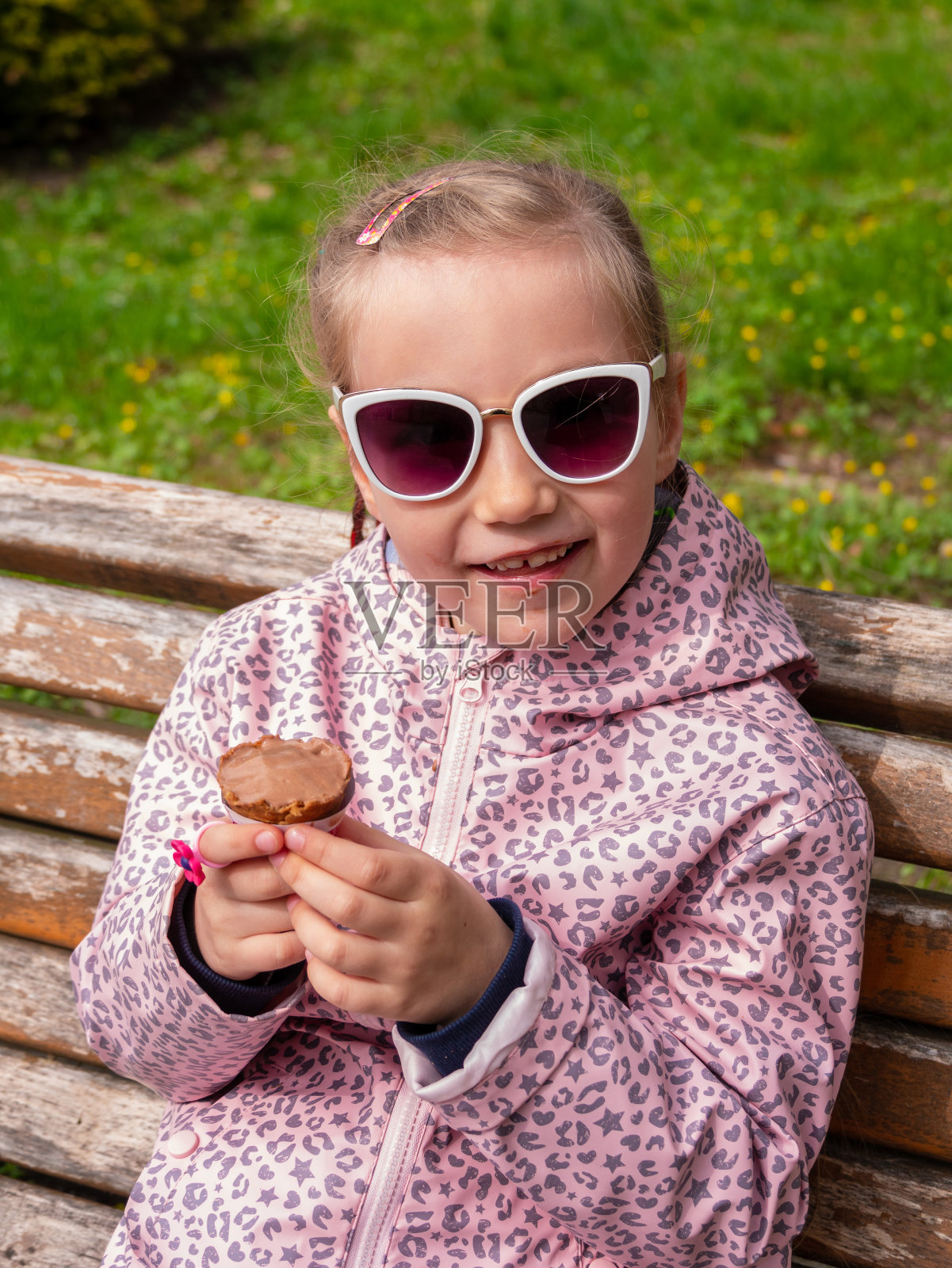 漂亮的小女孩在户外吃华夫筒里的冰淇淋。戴墨镜的孩子在绿色公园吃巧克力冰淇淋照片摄影图片