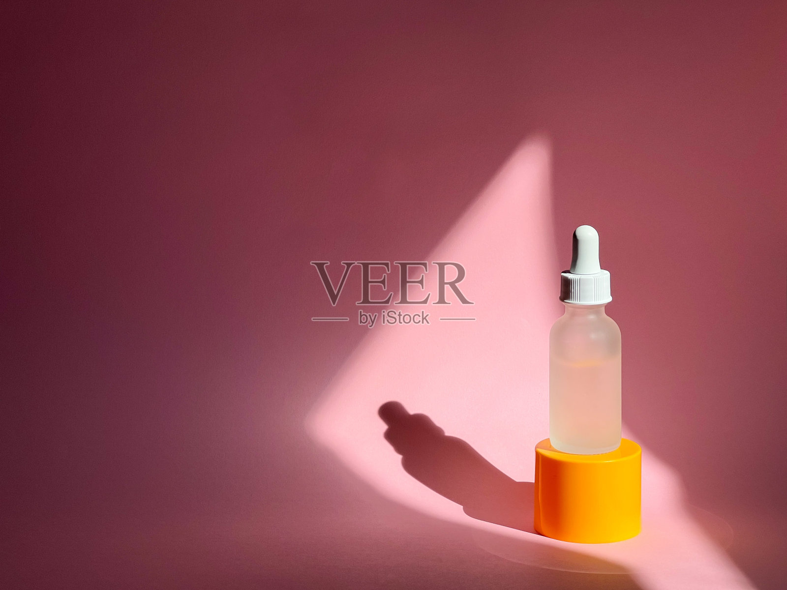 血清在一个玻璃滴管瓶在粉红色的背景。美容产品。护肤程序照片摄影图片