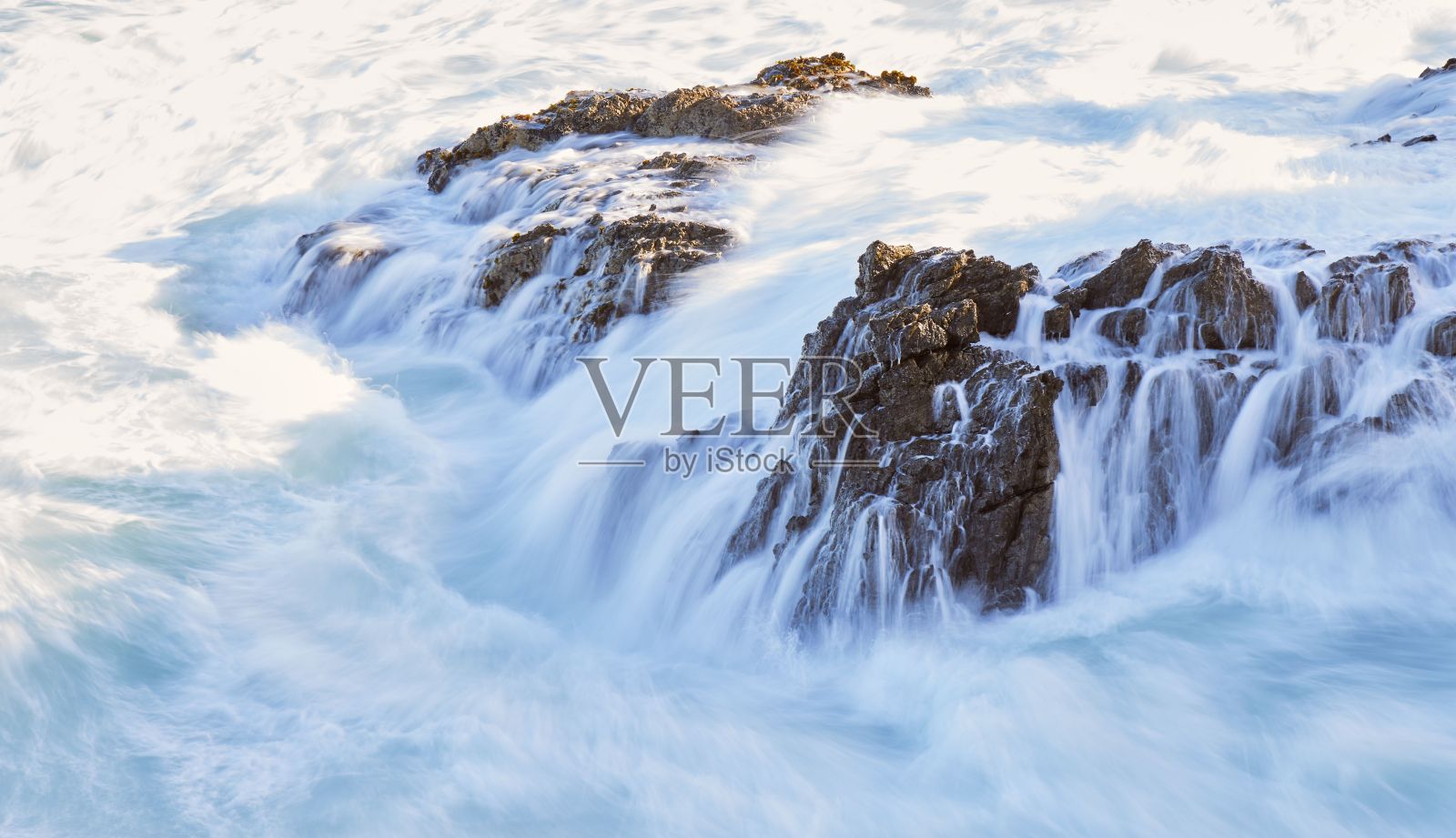 美丽的白色泡沫海浪撞击岩石的镜头。照片摄影图片