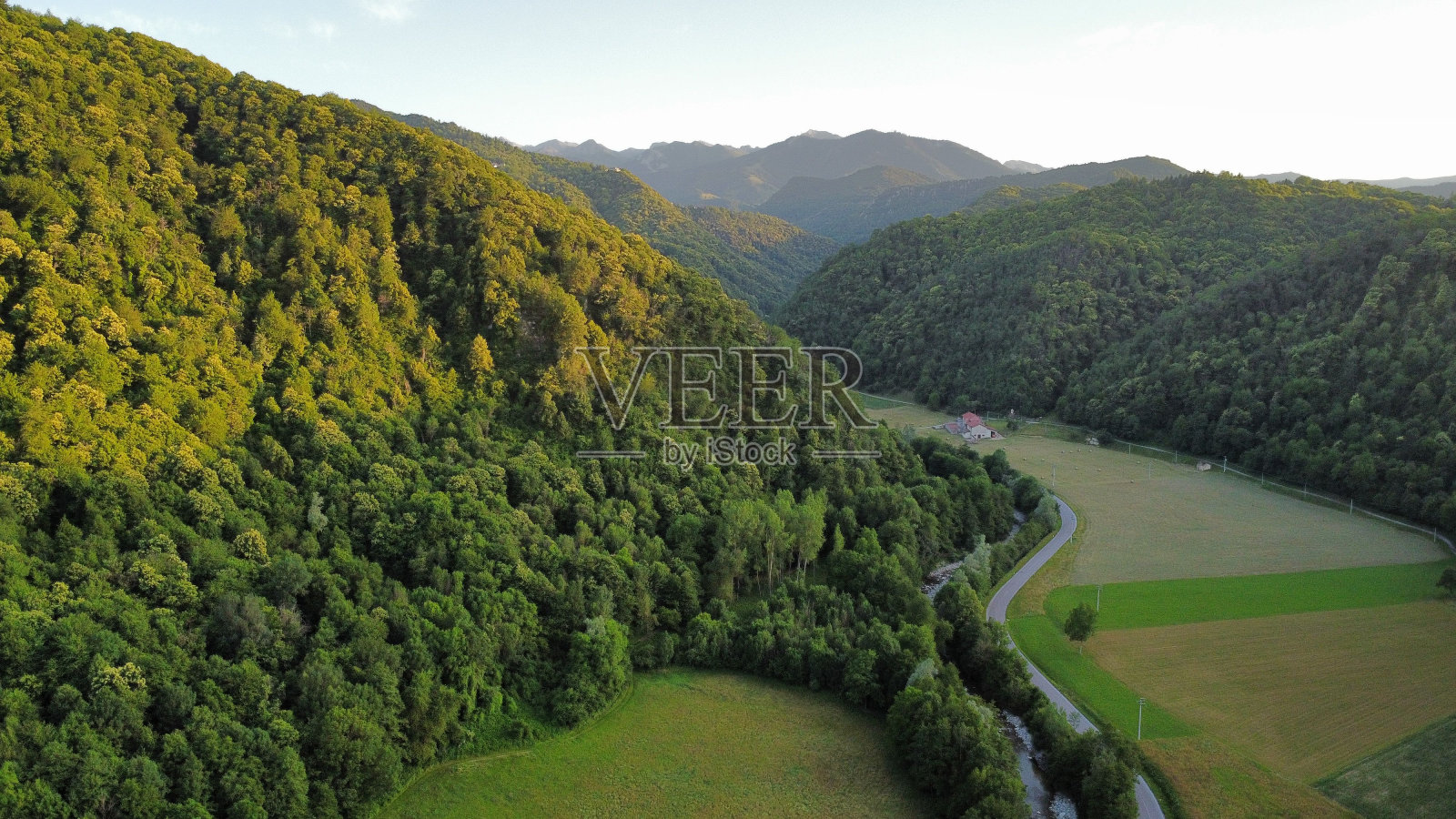航拍照片,一条蜿蜒的道路穿过郁郁葱葱的山谷,两侧是连绵起伏的山丘和树木照片摄影图片