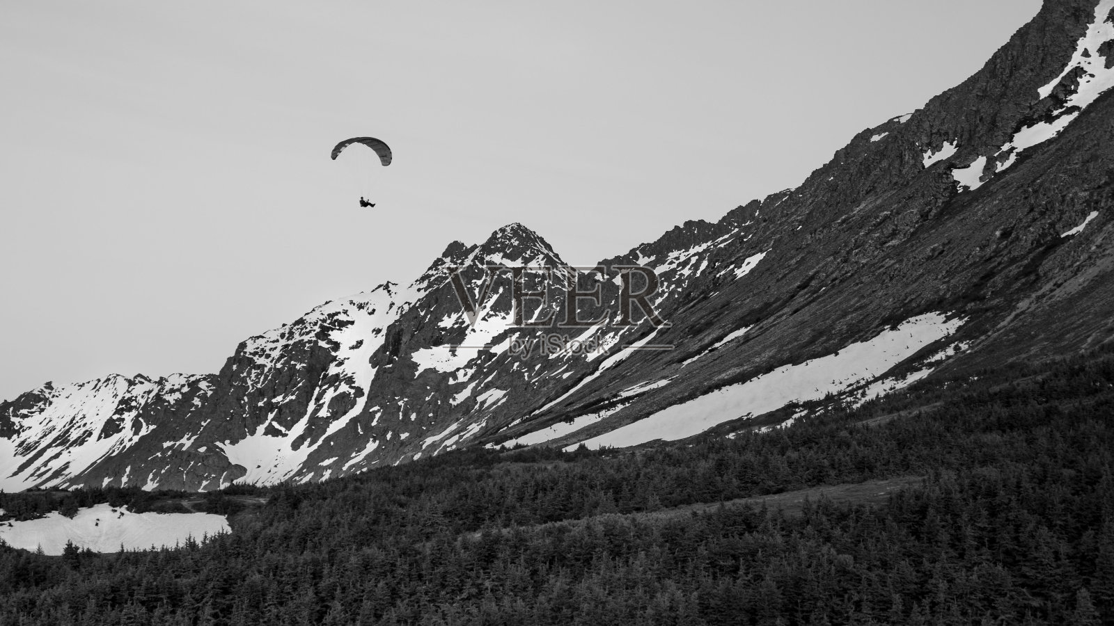 一个人滑翔伞的灰度图,他的降落伞在风中翻滚照片摄影图片