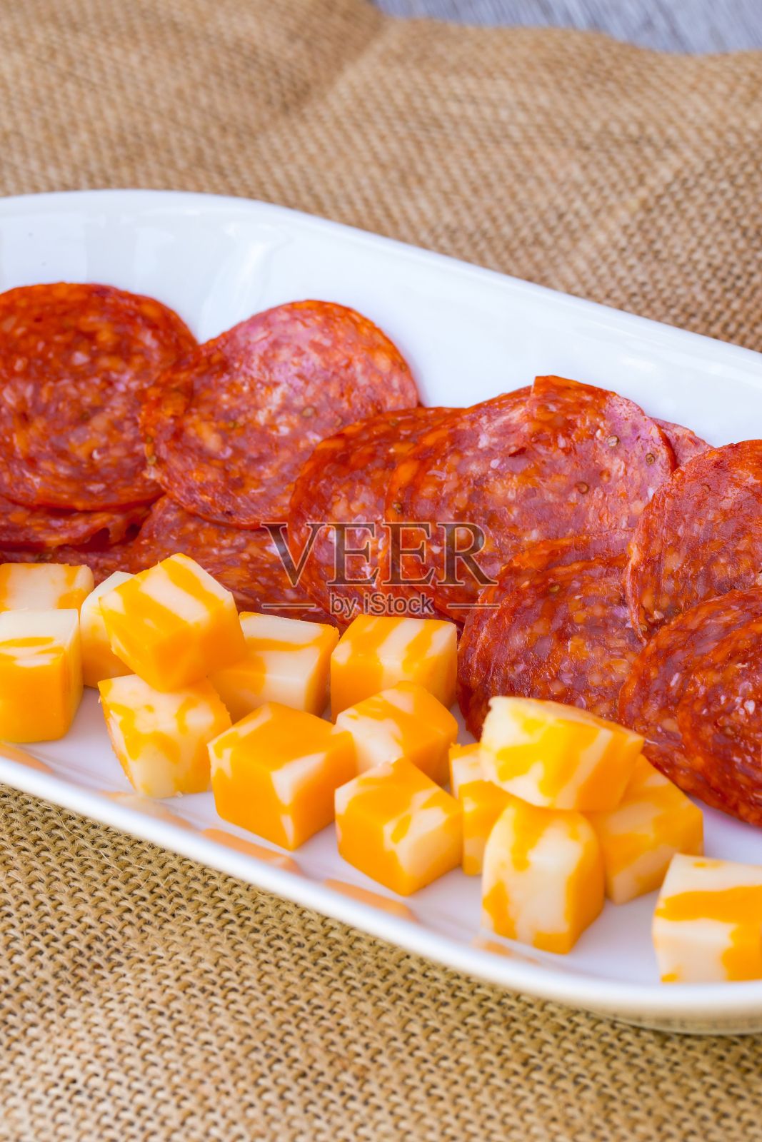 白色长拼盘,配芝士切片和意大利辣香肠。照片摄影图片