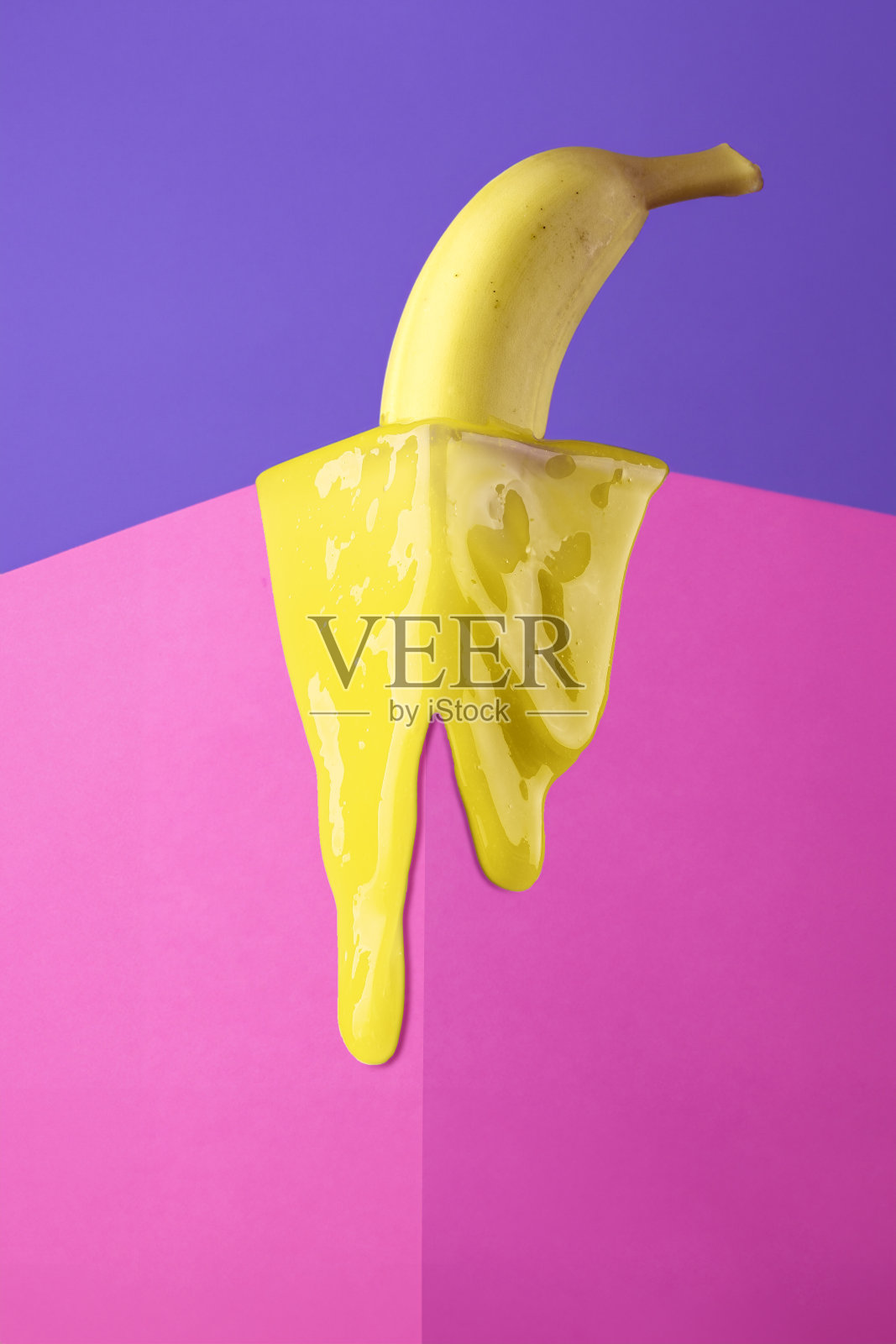 黄香蕉融化在粉色立方体的角落里。创意水果概念。照片摄影图片