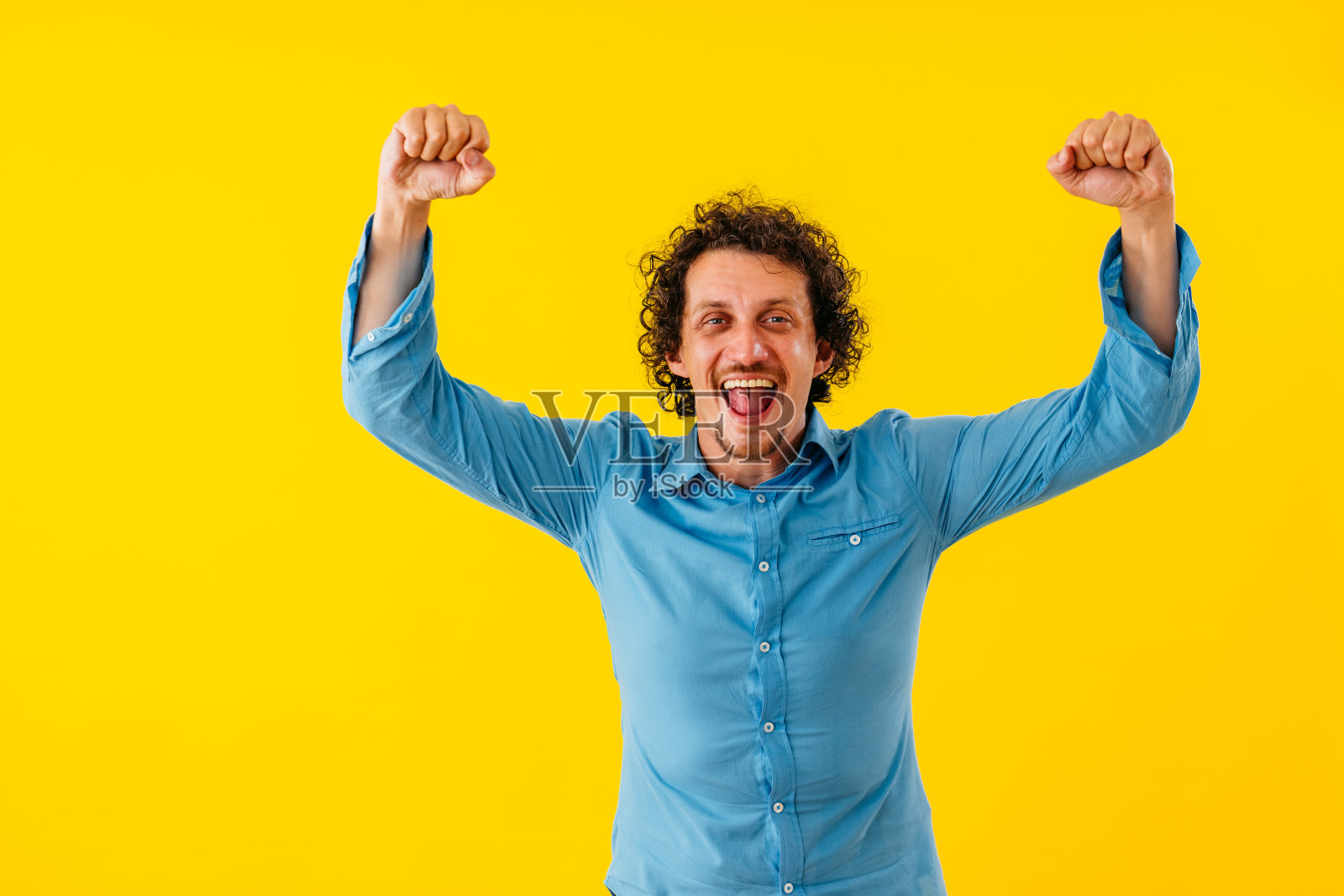 快乐的年轻人站在一堵黄色的墙前欢呼照片摄影图片