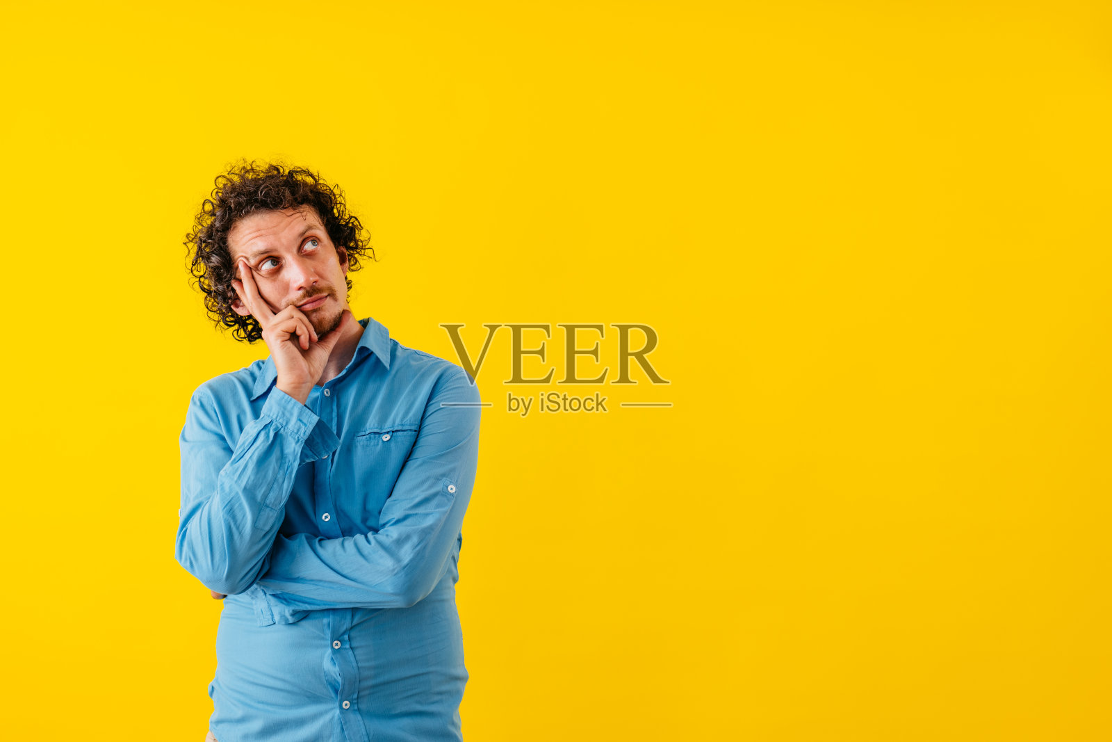 站在黄墙前沉思的年轻人照片摄影图片